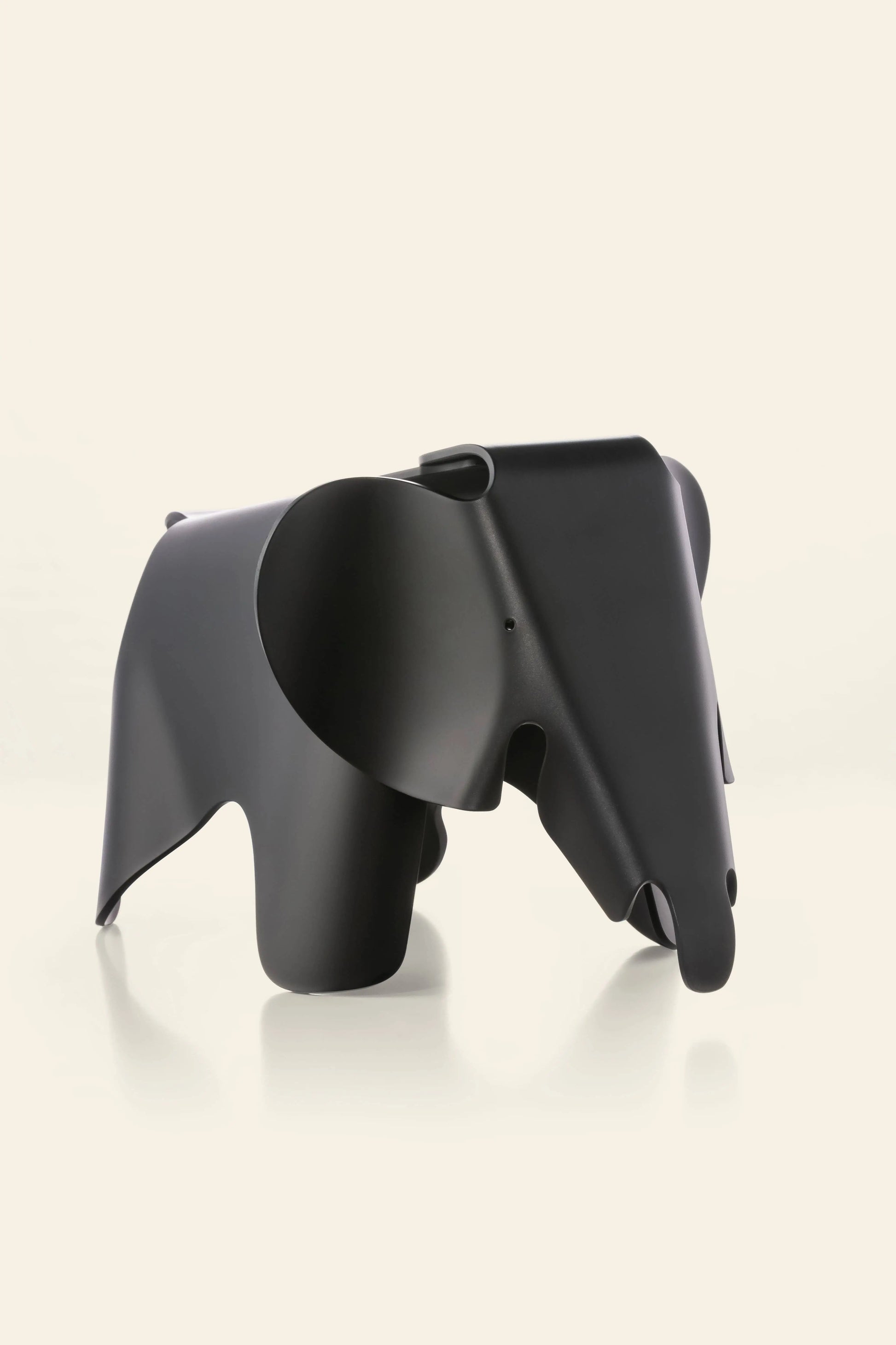 The Vitra Eames Elephant, Small by Vitra is a black, minimalist figurine made of smooth material, displayed against an off-white background. Its abstract design with simplified forms adds a decorative touch, inspired by the iconic Eames Elephant.
