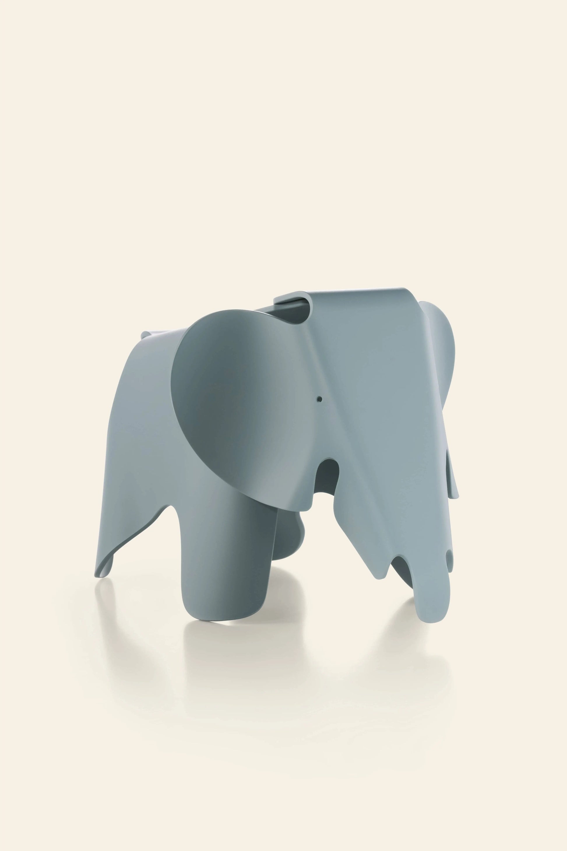 The Vitra Eames Elephant, Small by Vitra is a light blue, minimalist sculpture with smooth curves and oversized ears, displayed on a light beige background. This modern decorative piece features iconic design and simple shapes.