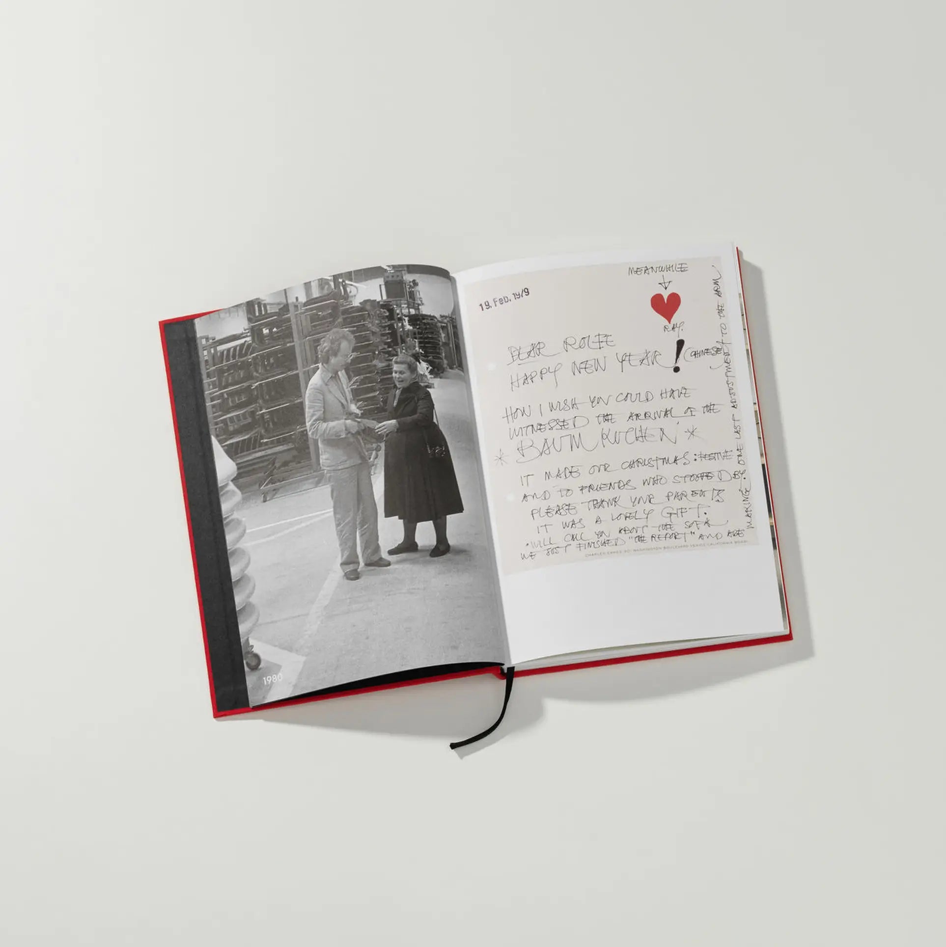 The Vitra Eames & Vitra Hardcover Book by Vitra shows a black-and-white photo of two people on the left page and a handwritten letter with a red heart on the right, reflecting the timeless design spirit of Charles and Ray Eames.