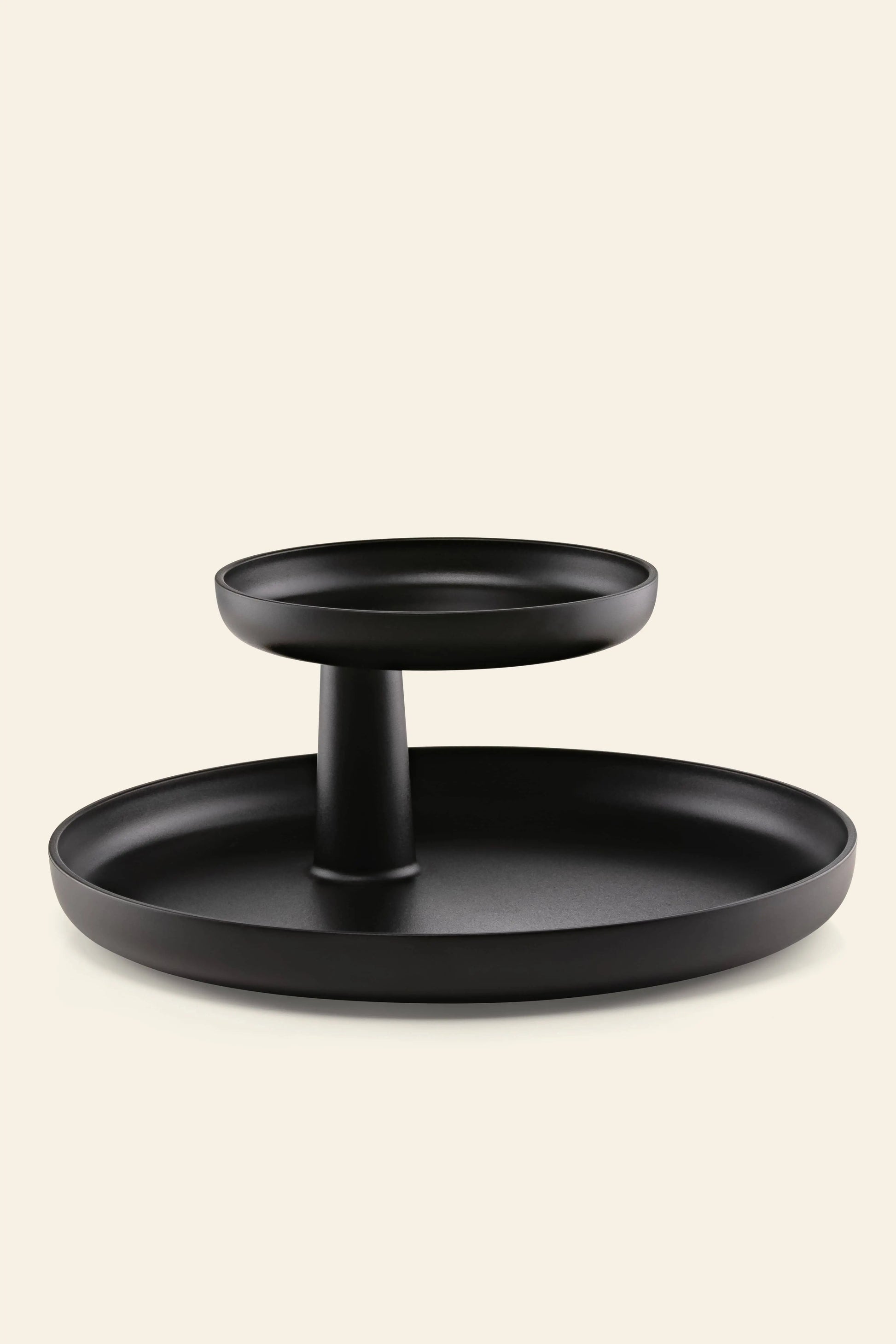 The Vitra Rotary Tray by Vitra is a stylish black, two-tiered organizer with a wide base and elevated top plate, perfect for organizing your belongings, shown against a plain beige background.