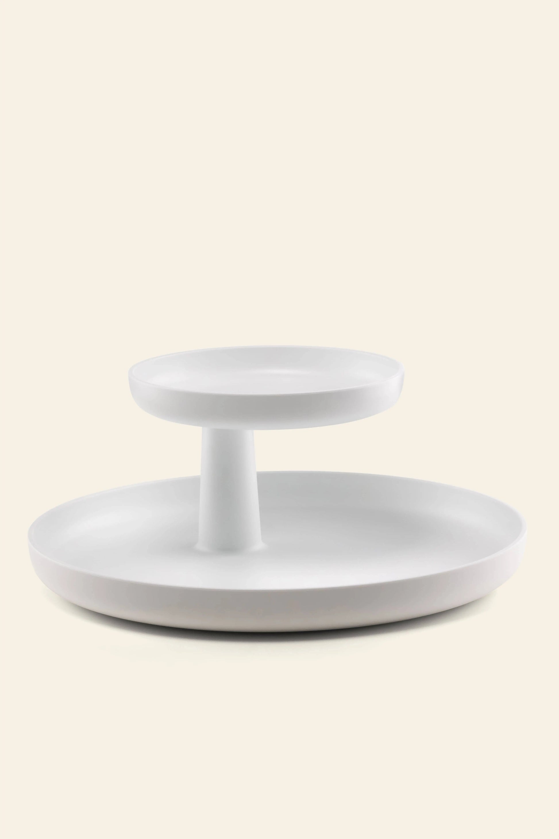 The Vitra Rotary Tray by Vitra is a minimalist, modern two-tiered white tray with a central column for stylish storage, showcased against an off-white background.