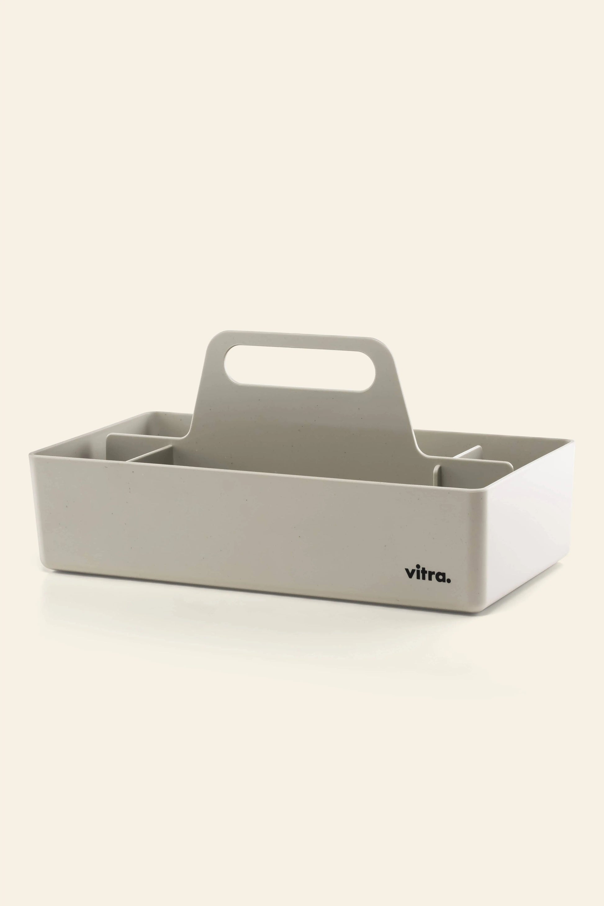 The Vitra Toolbox RE by Vitra is a white rectangular caddy made from recycled ABS plastic, featuring a central handle, multiple compartments, and the Vitra logo on the front.