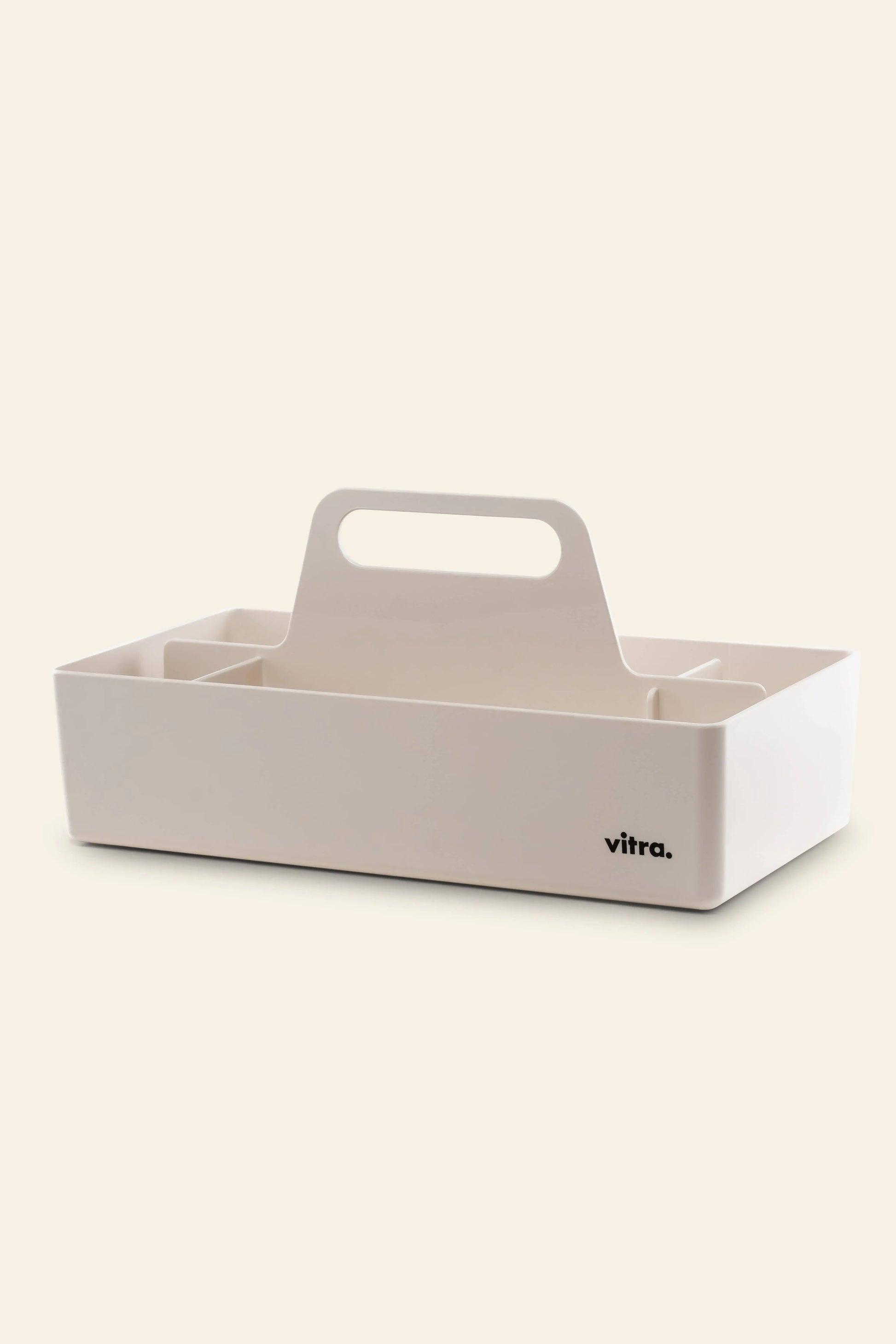 The Vitra Toolbox RE is a white rectangular caddy made from recycled ABS plastic, with compartments, a central handle, and the Vitra logo—ideal as a table accessory.