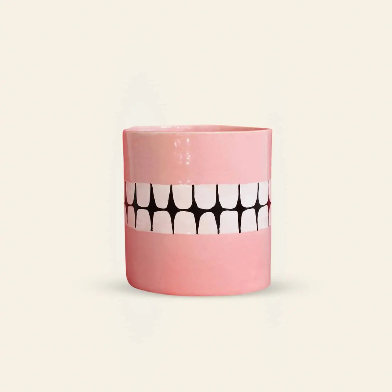 The Wobbly Studio Denture Pot by Wobbly Studio is a pink cylindrical planter with a bold, toothy smile graphic circling its center, adding playful charm to any off-white background.