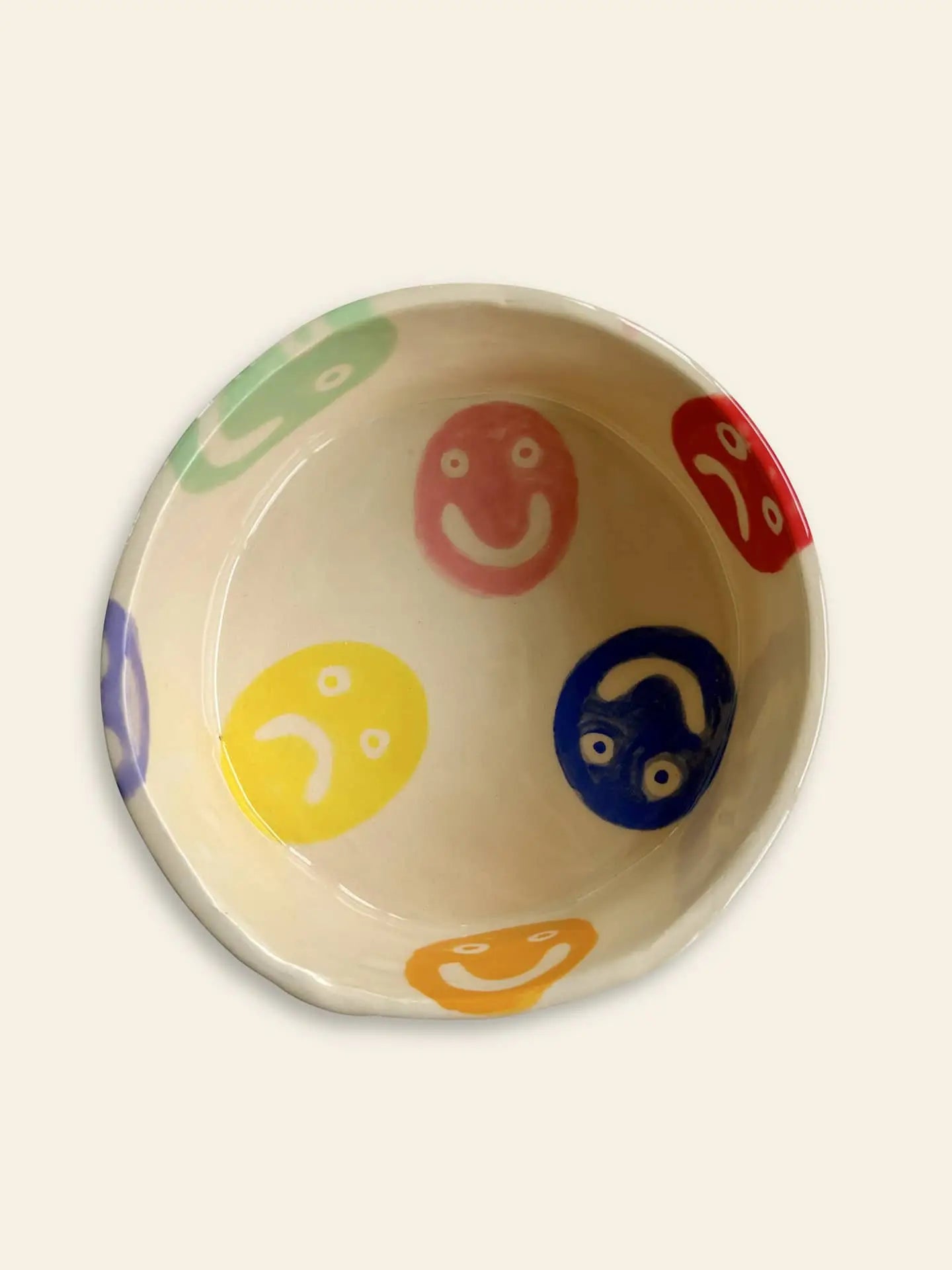 The Wobbly Studio Doggo Bowl, Bigger by Wobbly Studio features multicolour smiley and sad faces in red, blue, yellow, green, orange, and purple on a handcrafted white ceramic bowl.