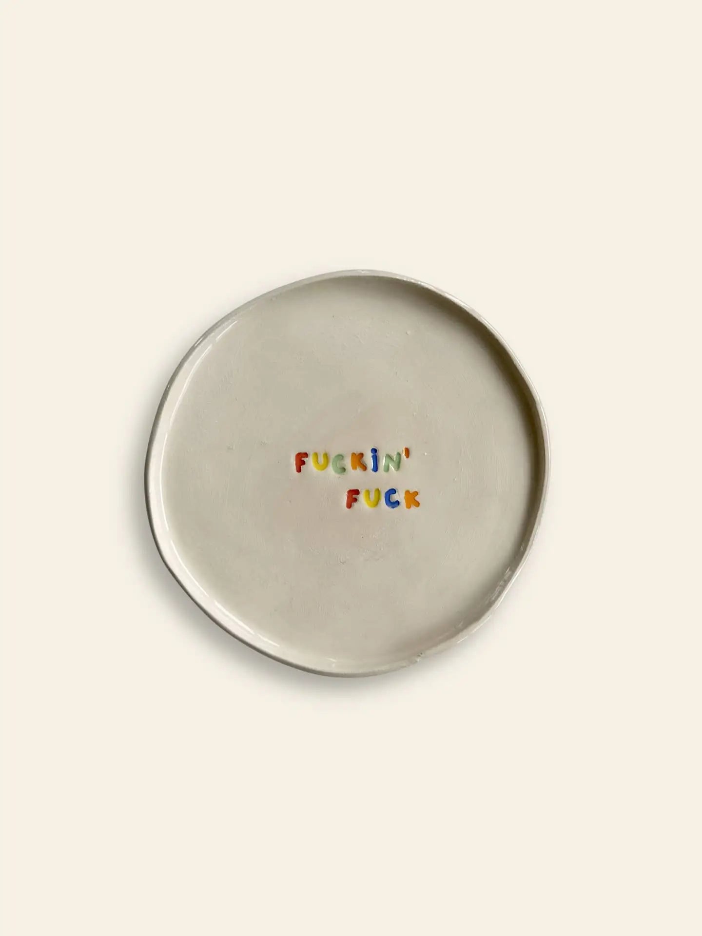 The Wobbly Studio Mini Plate - Fuckin Fuck is a handcrafted white ceramic plate featuring FUCKIN FUCK in colorful letters—a playful, bold piece by Wobbly Studio for fans of cheeky designs.