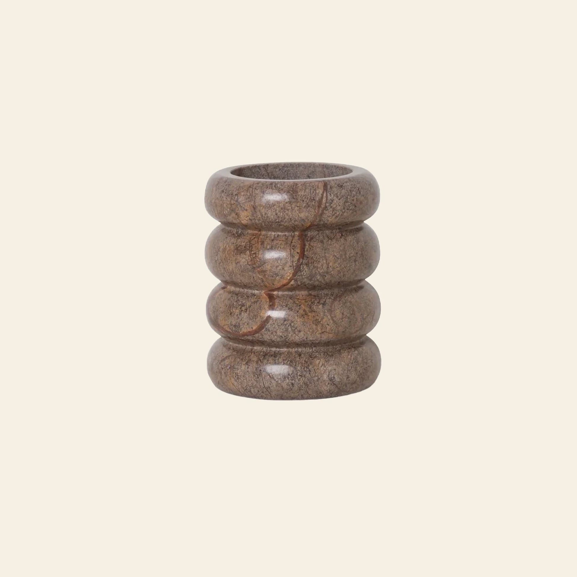 The ferm LIVING Bendum Cup by ferm LIVING is a brown cylindrical cup crafted from Brown Bidasar marble, with four rounded stacked rings that highlight its geometric form, displayed on a plain light beige background.