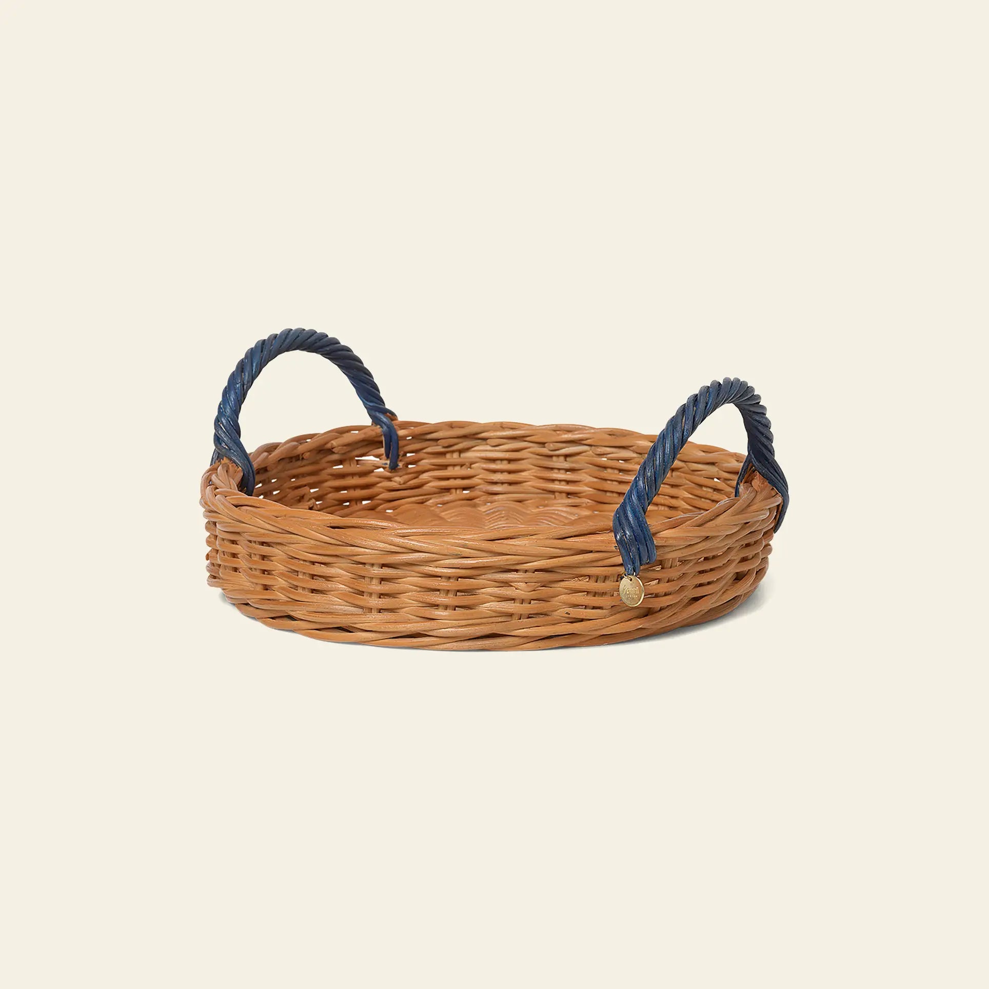The ferm LIVING Blue Handle Tray is a round rattan tray with two dark blue handles, shown against a plain light background.