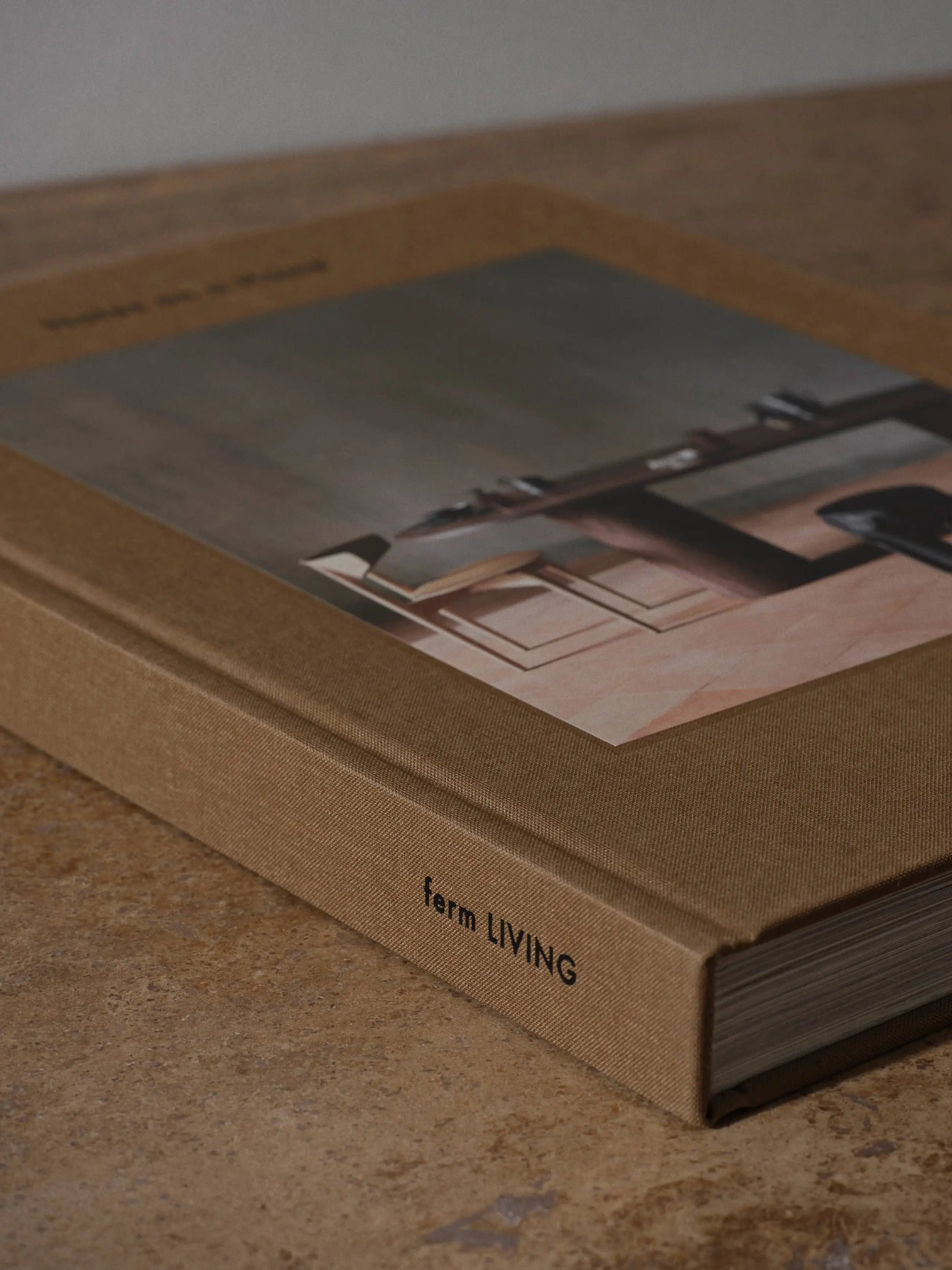 The ferm LIVING Coffee Table Book 2023 features a brown textured hardcover and minimalist interior photos, capturing the brand’s design concept and creative process, with ferm LIVING printed on the spine.