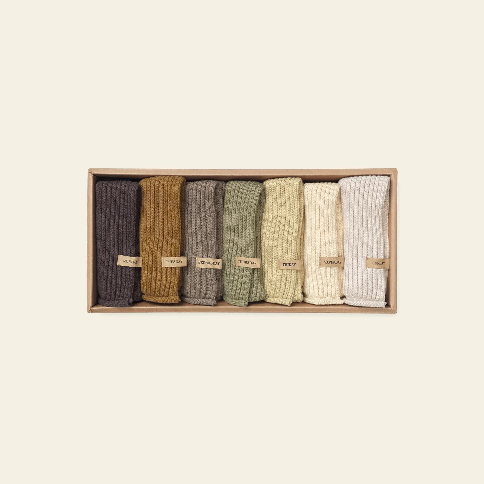 The ferm LIVING Day Cloths, Set of 7, features seven soft cloths in earth tones. Each is neatly rolled and labeled, crafted from organic cotton with GOTS certification—offering comfort and sustainable style from ferm LIVING.