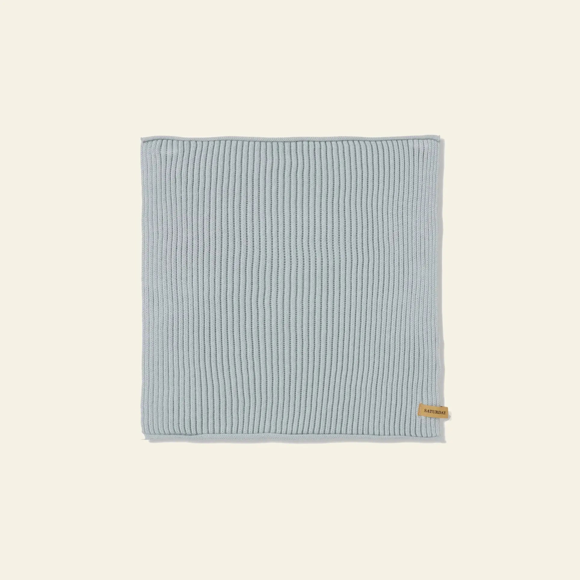A set of seven neatly folded ferm LIVING Day Cloths, made from GOTS-certified organic cotton in light blue with a small brown tag, is displayed on a plain beige background.