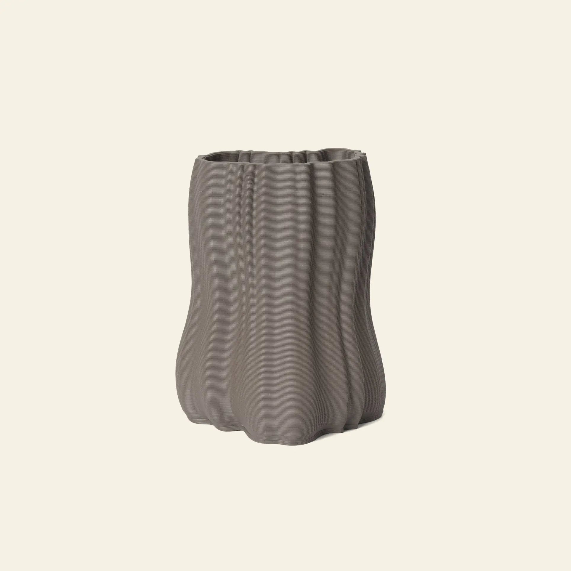 The ferm LIVING Moire Vase, Small, in gray features a wavy vertical ribbed texture and organic shape, echoing 3D-printed clay. It stands out against a plain light beige background, highlighting its distinctive design by ferm LIVING.