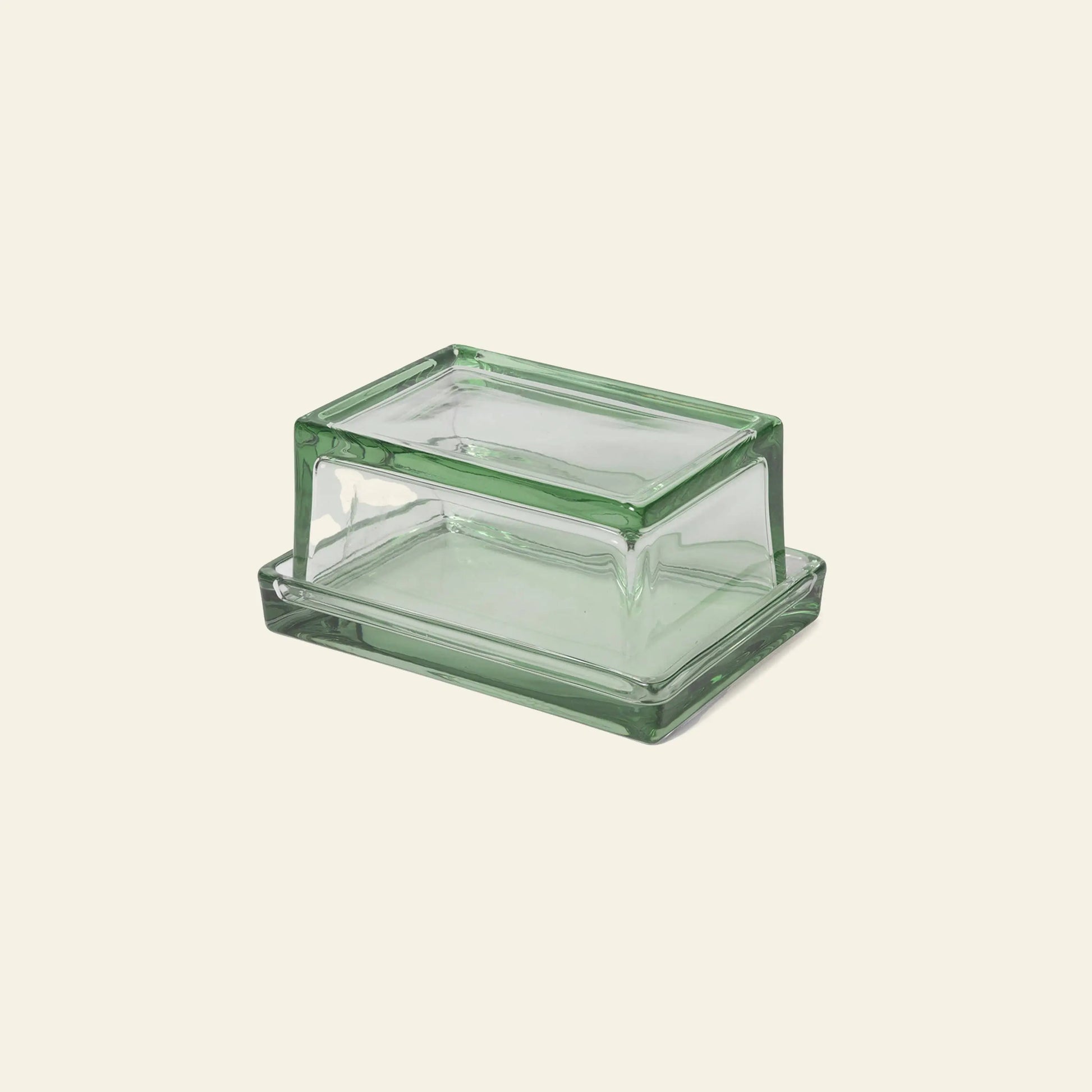 The ferm LIVING Oli Box, a rectangular green-tinted butter dish with matching lid made from recycled glass by ferm LIVING, is displayed on a plain beige background.