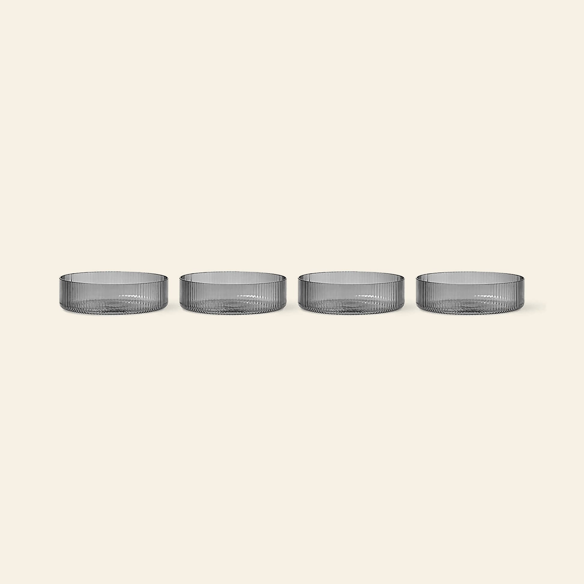 The ferm LIVING Ripple Serving Bowls, Set of 4—made from mouth-blown glass with a ribbed texture—are displayed in a row against a plain, light beige background.