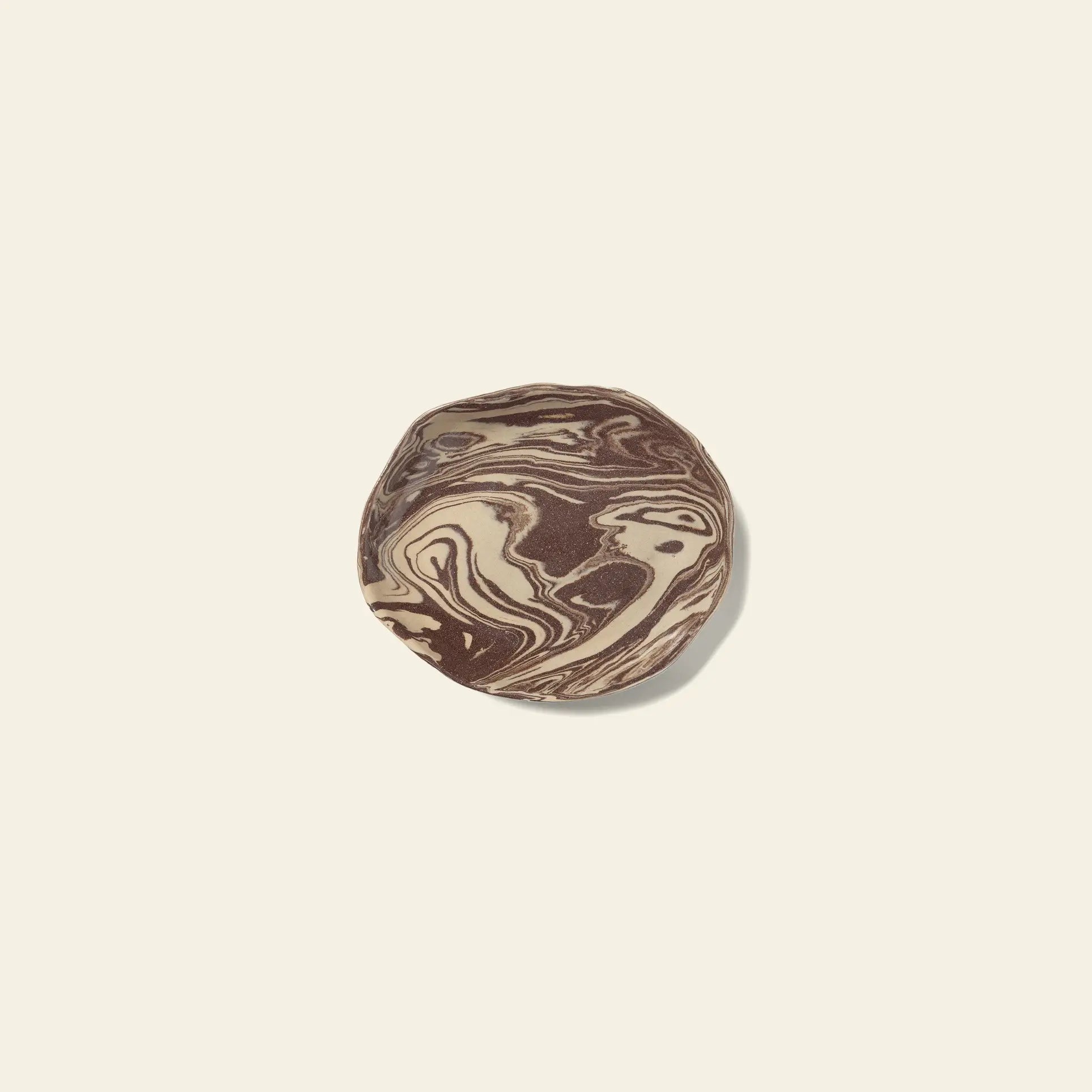The ferm LIVING Ryu Platter, 18.5cm, by ferm LIVING, features a round design with swirled chocolate and vanilla tones inspired by the Nerikomi technique, displayed on a plain light beige background.