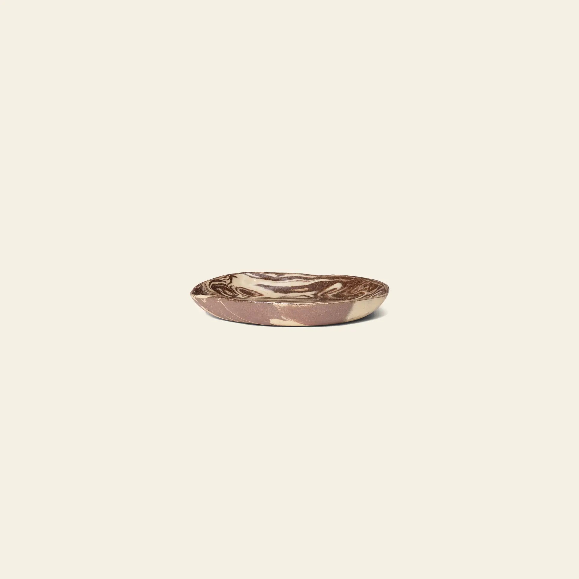 The ferm LIVING Ryu Platter, 18.5cm, features a small, shallow ceramic design with a brown and cream marbled pattern crafted using the Nerikomi technique, displayed on a plain light beige background.