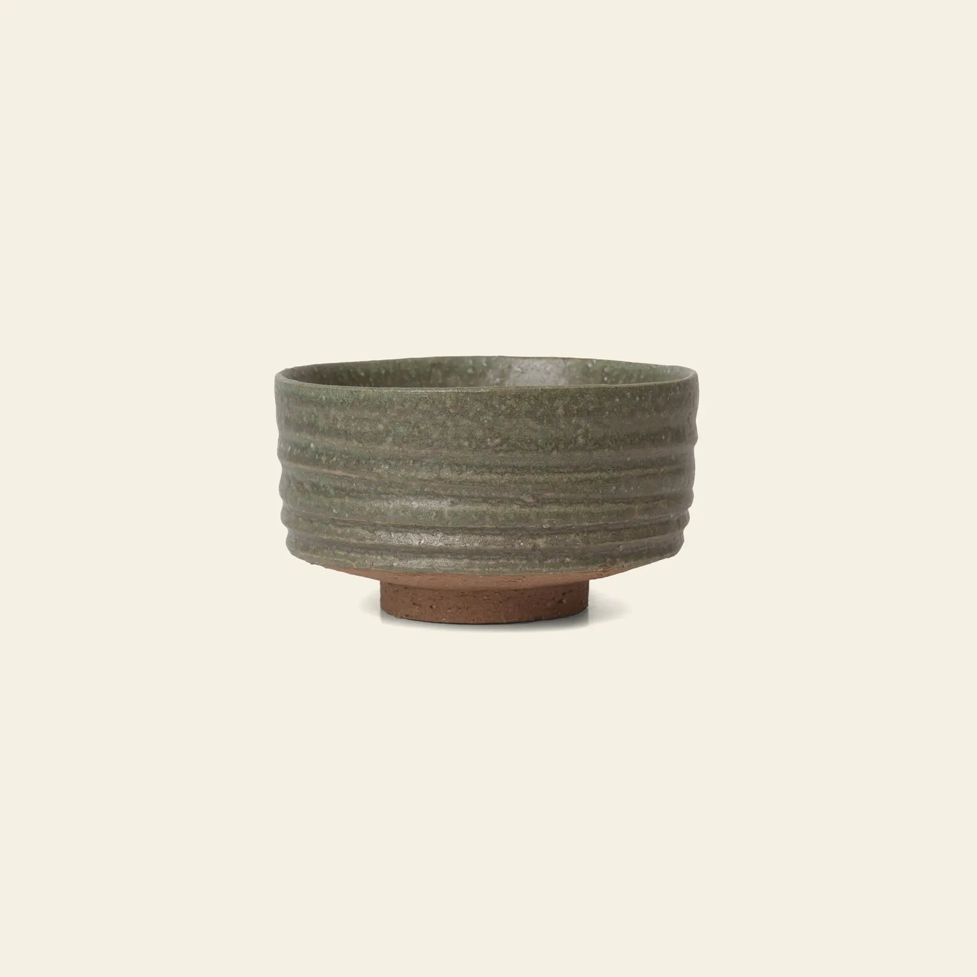 The ferm LIVING Serena Bowl, 12.5cm, features a luxurious mossy green reactive glaze with a ridged ceramic surface and sits on a small unglazed brown base, all crafted by ferm LIVING and shown against a light background.