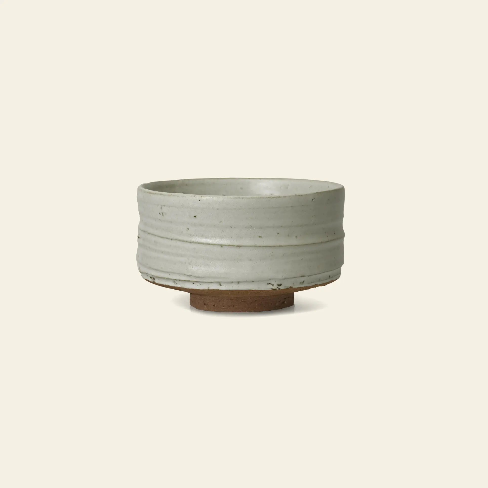The ferm LIVING Serena Bowl, 12.5cm, is a handmade ceramic piece with a smooth white glaze and subtle horizontal grooves, featuring a textured natural unglazed brown base, shown against a plain light background.