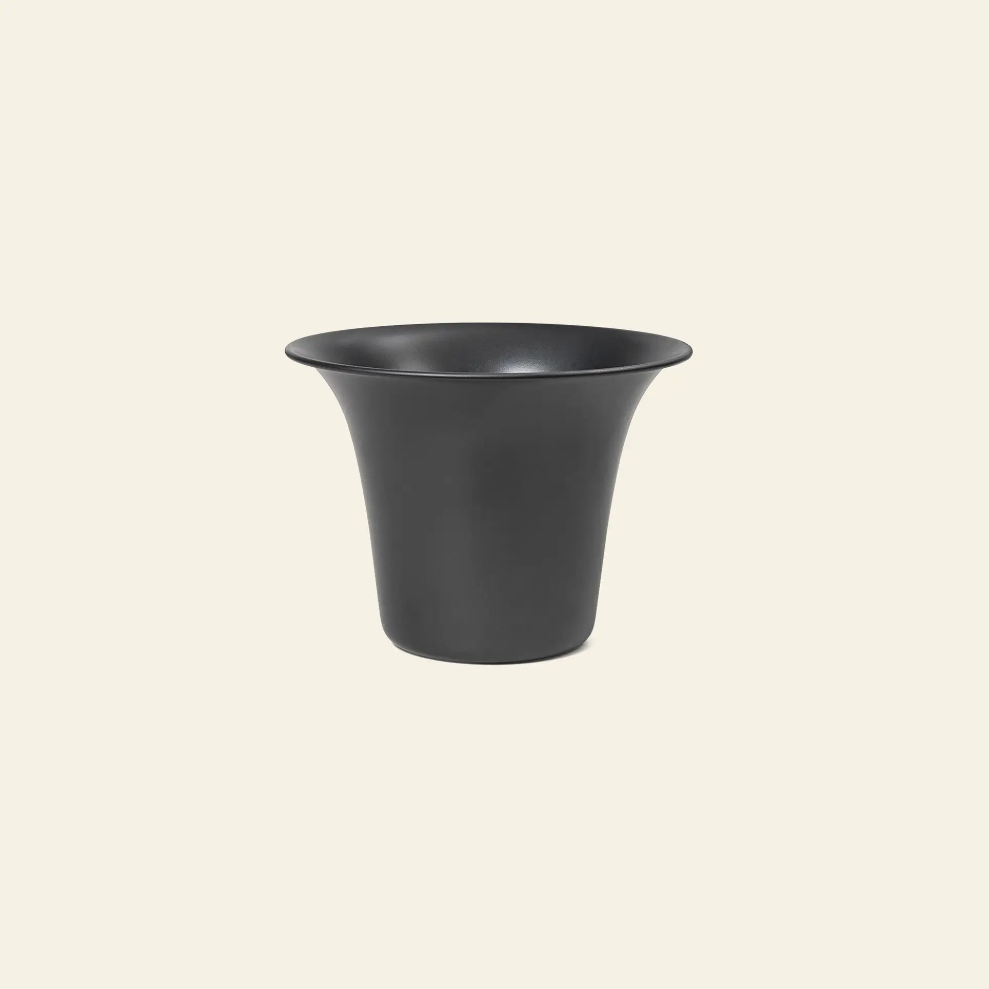 The ferm LIVING Spun Alu Pot, featuring a matte black metal finish, wide rim, and smooth flared aluminium design, is displayed against a plain light beige background.