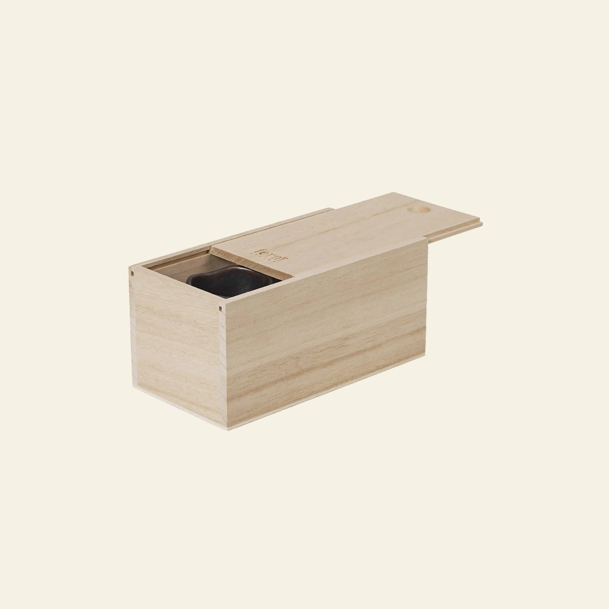 A minimalist light wooden box with a sliding lid, partially open to reveal a dark compartment—ideal for storing treasures like the ferm LIVING Uneru Mini Pots, Set of 2. The simple box is set against a plain off-white background.
