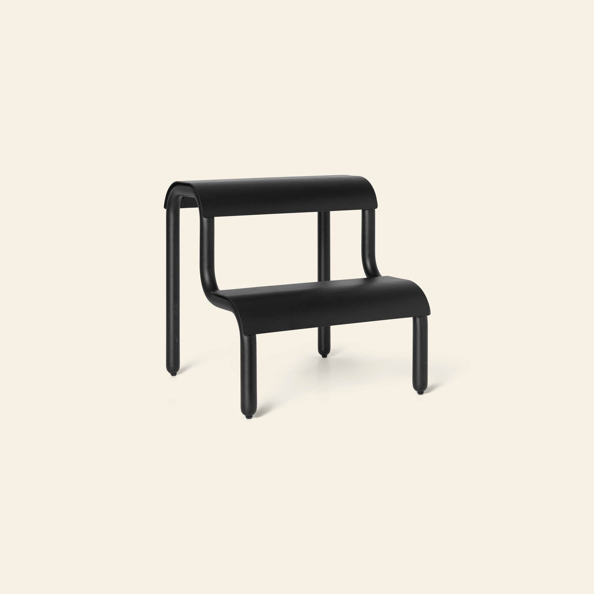 The ferm LIVING Up Step Stool by ferm LIVING is a modern black stool made of powder-coated iron, with two rounded textured steps and four cylindrical legs, displayed against a light beige background.