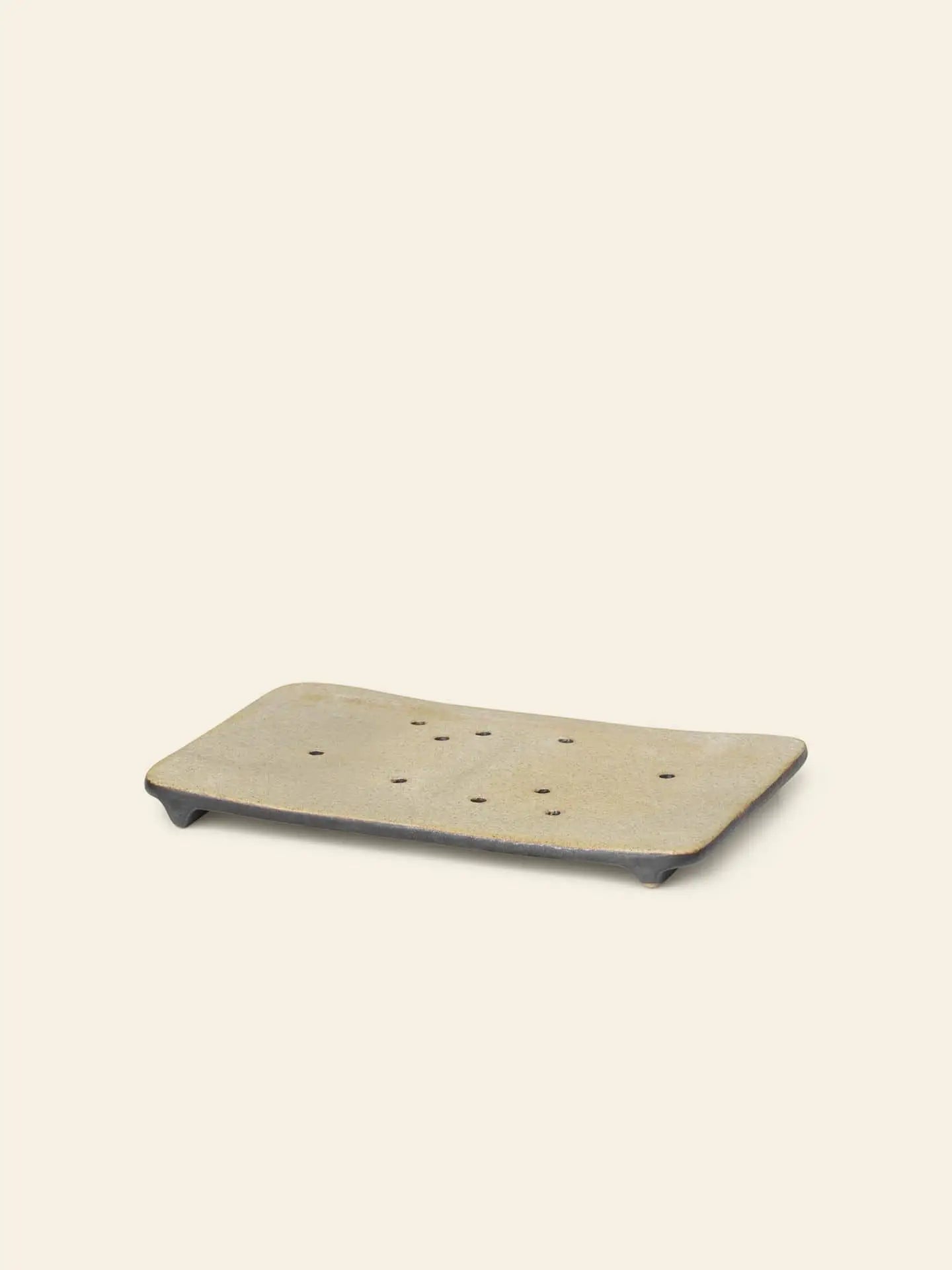 The ferm LIVING Bon Accessories Soap Tray is a rectangular beige porcelain tray with drainage holes and short feet, adding elegance to your bathroom. Displayed on a plain light background.