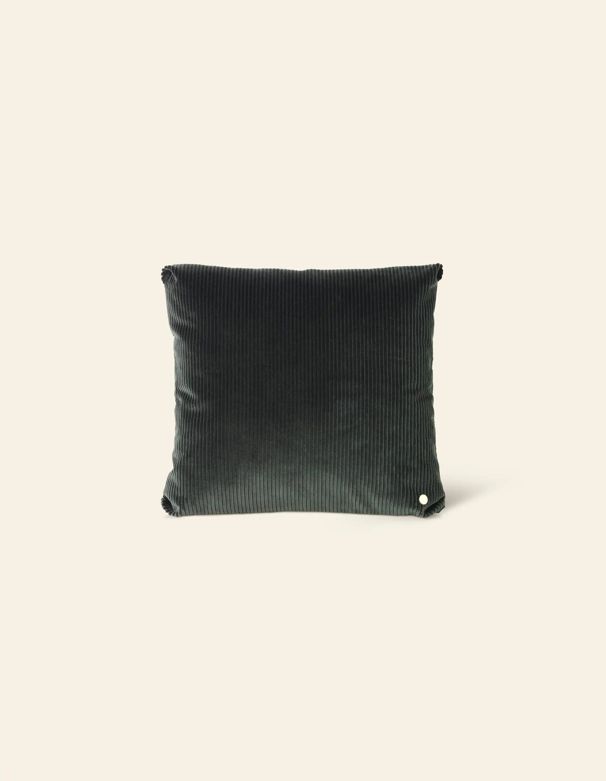 The ferm LIVING Corduroy Cushion, a square pillow in dark green with a ribbed texture, sits upright against a plain light beige background—an elegant accent from ferm LIVING.