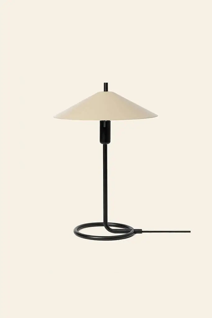 The ferm LIVING Filo Table Lamp features a powder-coated iron black stem and a beige cone shade, offering modern style to any room. Its circular base and exposed cord add to its sleek look, perfect for bright spaces.