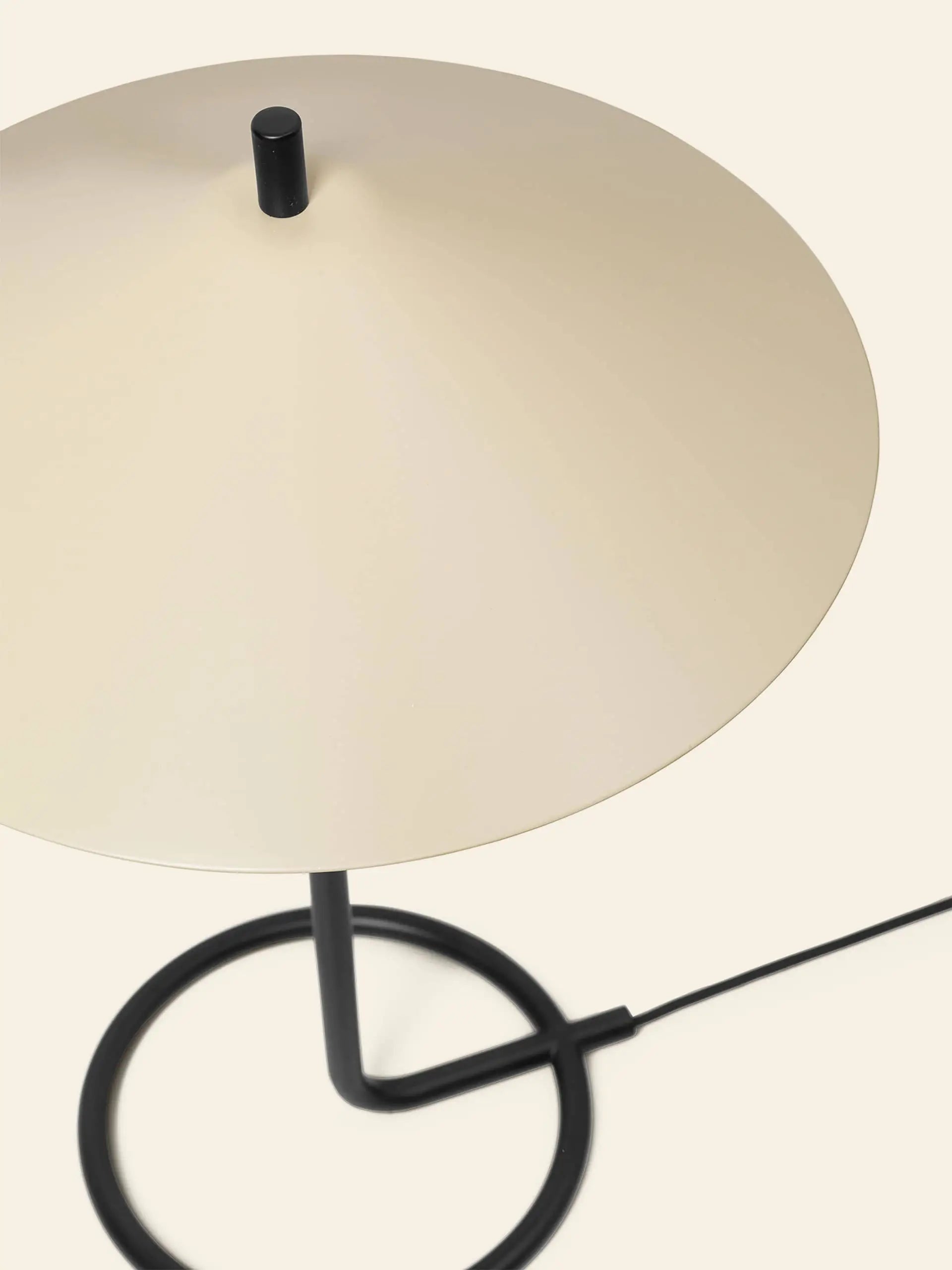 The ferm LIVING Filo Table Lamp features a flat, circular beige shade, black powder coated stem, and round black base with a power cord—an ideal minimalist accent for modern homes.
