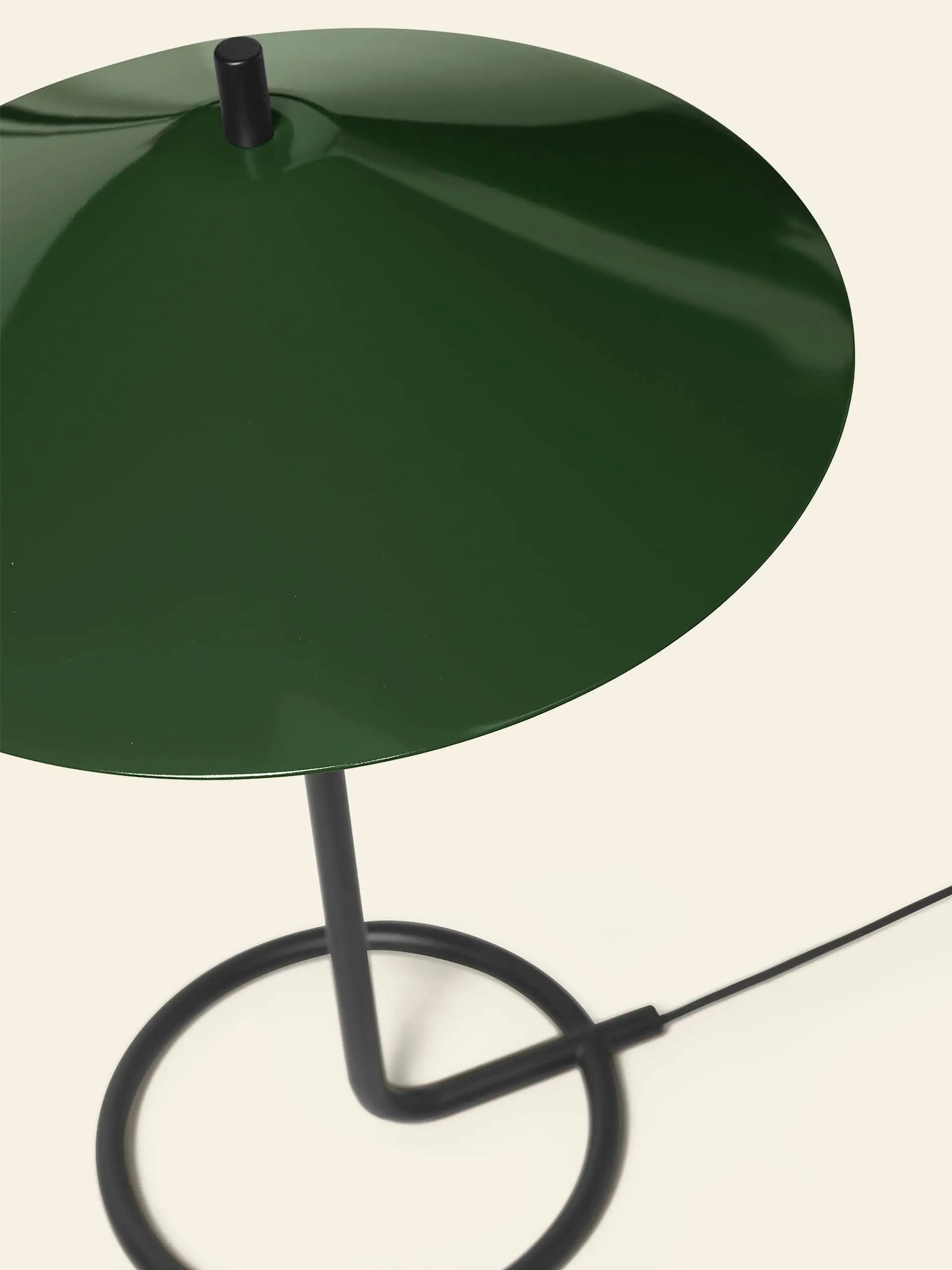 The ferm LIVING Filo Table Lamp by ferm LIVING showcases a glossy dark green, cone-shaped powder coated iron shade and a black circular base with a black power cord, ideal for modern homes.