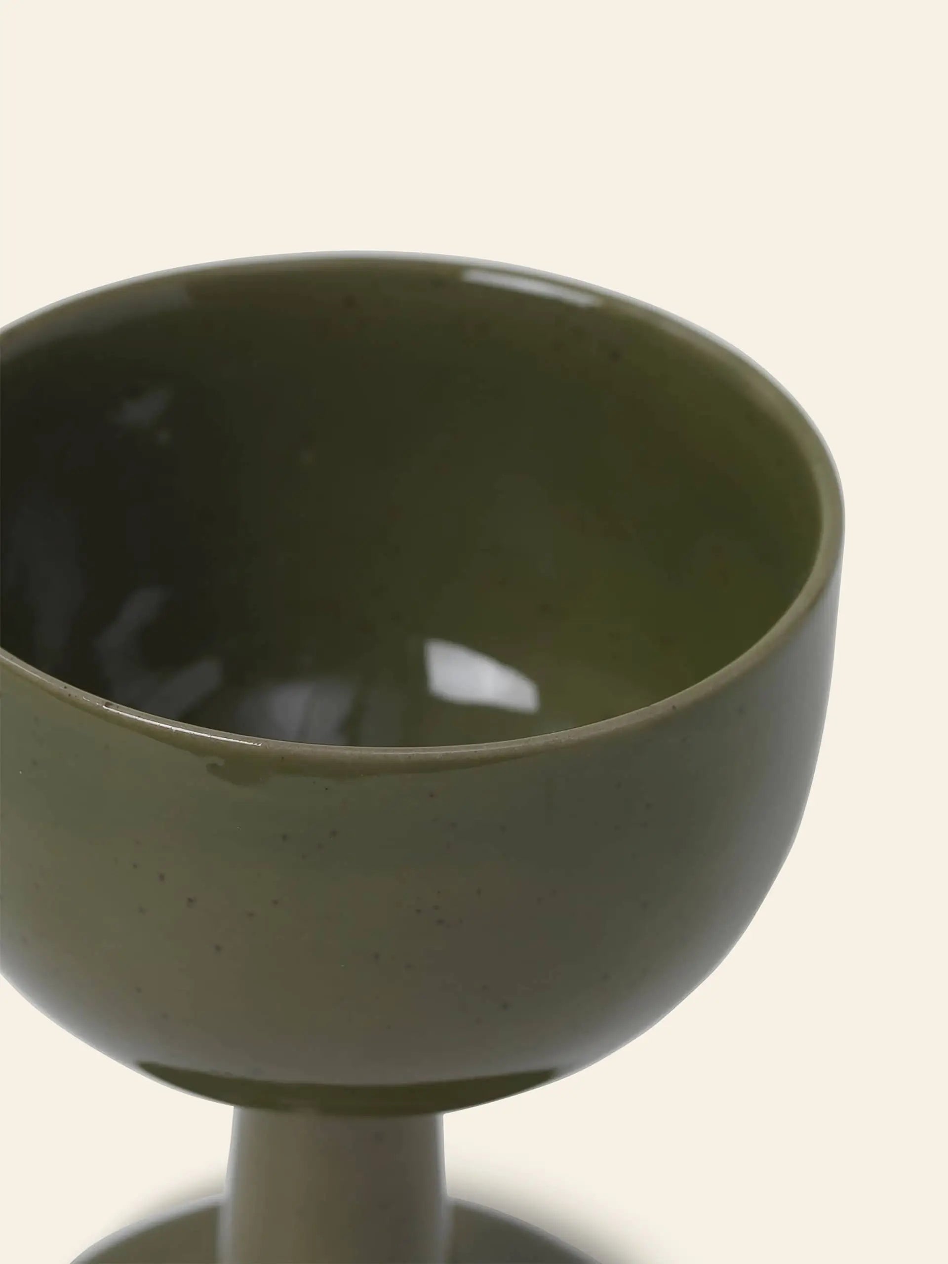A close-up of the ferm LIVING Floccula Wine Glass in green, partially filled and set against a plain light background—capturing the charm of French bistros.