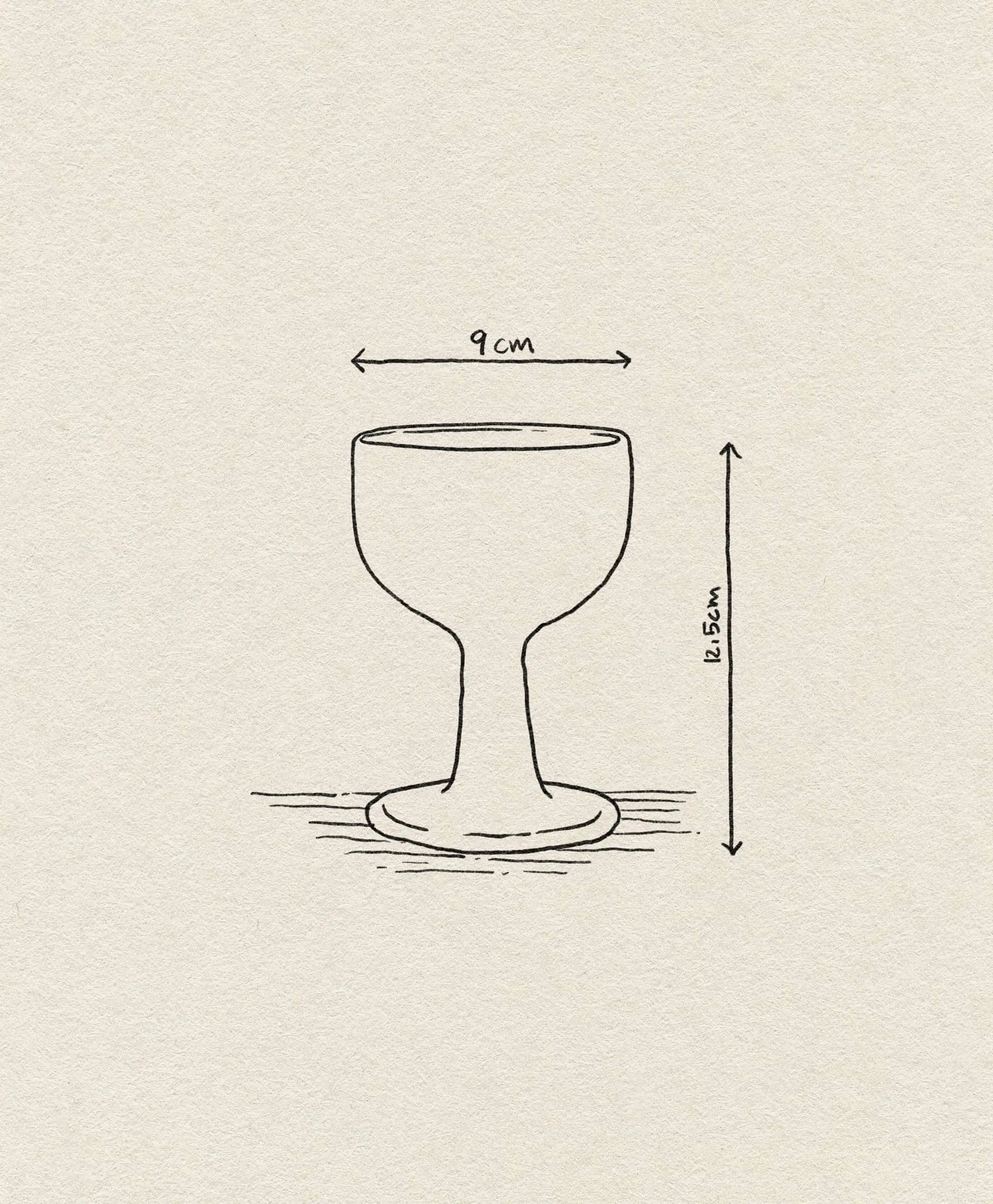 A line drawing of the ferm LIVING Floccula Wine Glass, shaped like a balloon wine glass with a wide base, labeled 9 cm wide and 11.5 cm tall, is set against a textured off-white paper background.