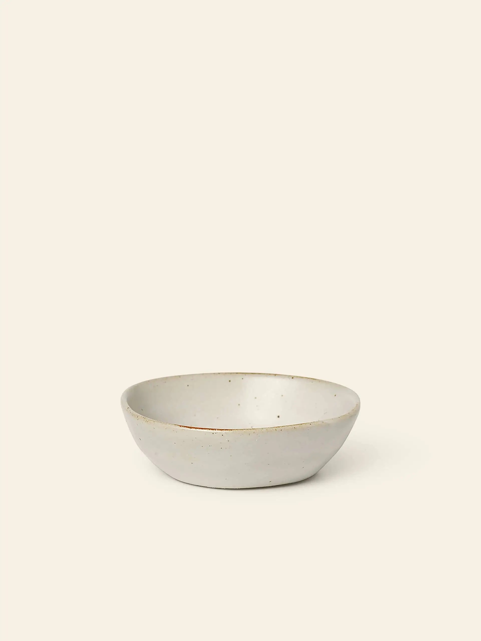 The ferm LIVING Flow Porcelain Bowl, Small, features a minimalist, off-white design and shallow round shape—an elegant piece of artisanal tableware from the renowned brand ferm LIVING.