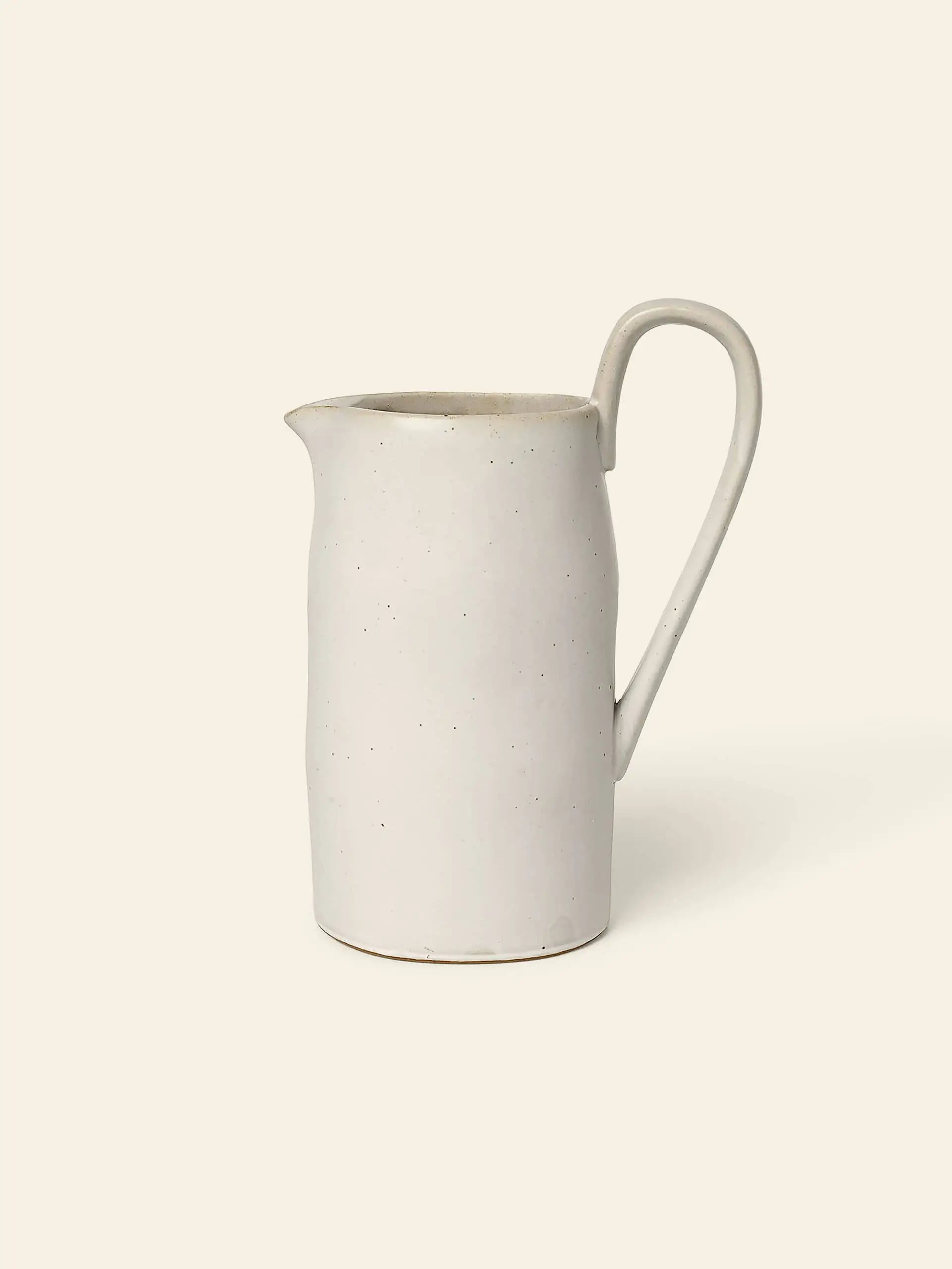 The ferm LIVING Flow Jug by ferm LIVING is a simple off-white ceramic piece with organic curves, a curved handle, and narrow spoutโideal for minimalist kitchen decor.