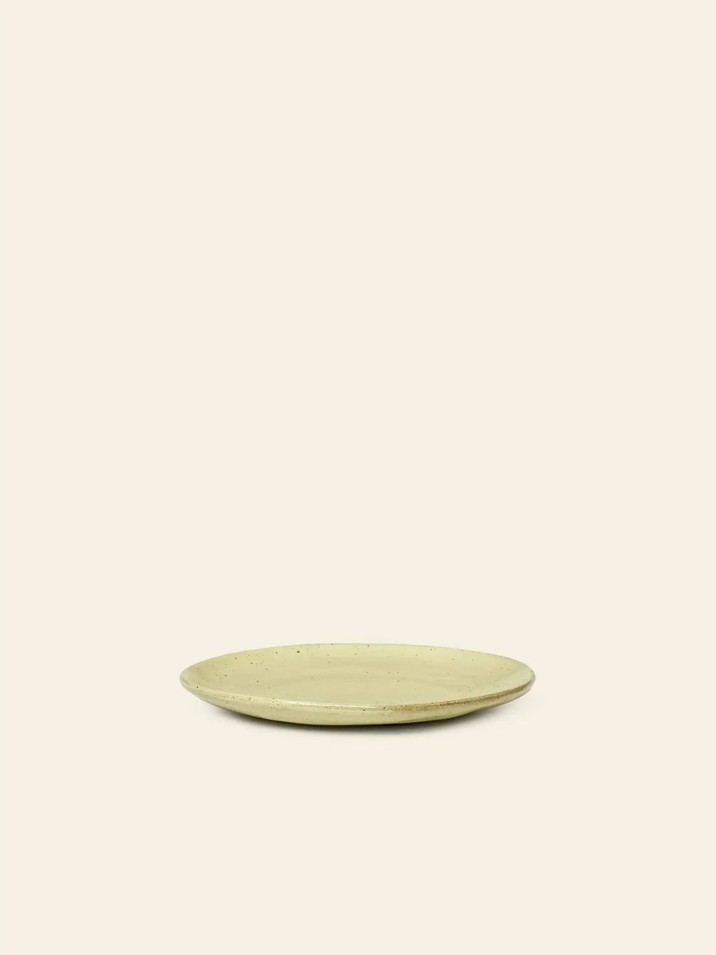 The ferm LIVING Flow Plate, Small, features a simple round shape in beige porcelain with a slightly raised rim, displayed centered against a plain, light background.