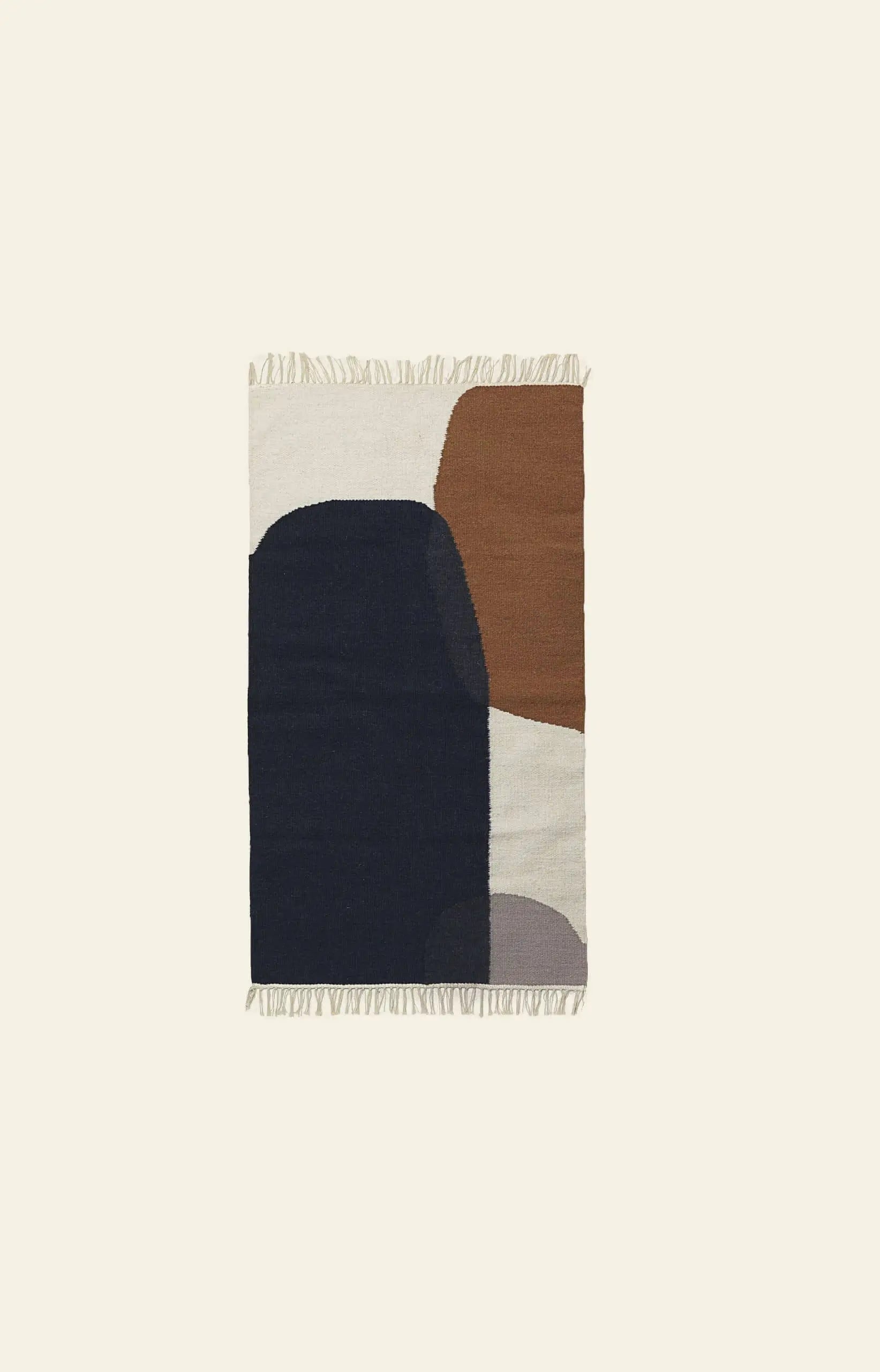 The ferm LIVING Kelim Rug by ferm LIVING features abstract geometric shapes in navy blue, brown, beige, and gray on a rectangular design with short fringe on the ends, shown against a plain light background.