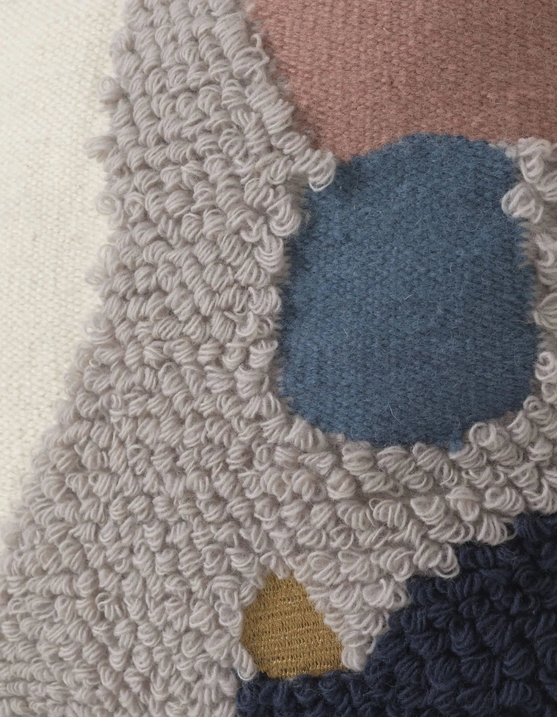 Close-up of the ferm LIVING Loop Cushion, crafted from New Zealand wool with looped gray yarn, blue oval, mustard yellow, dark blue accents, and muted pink for a modern abstract look.