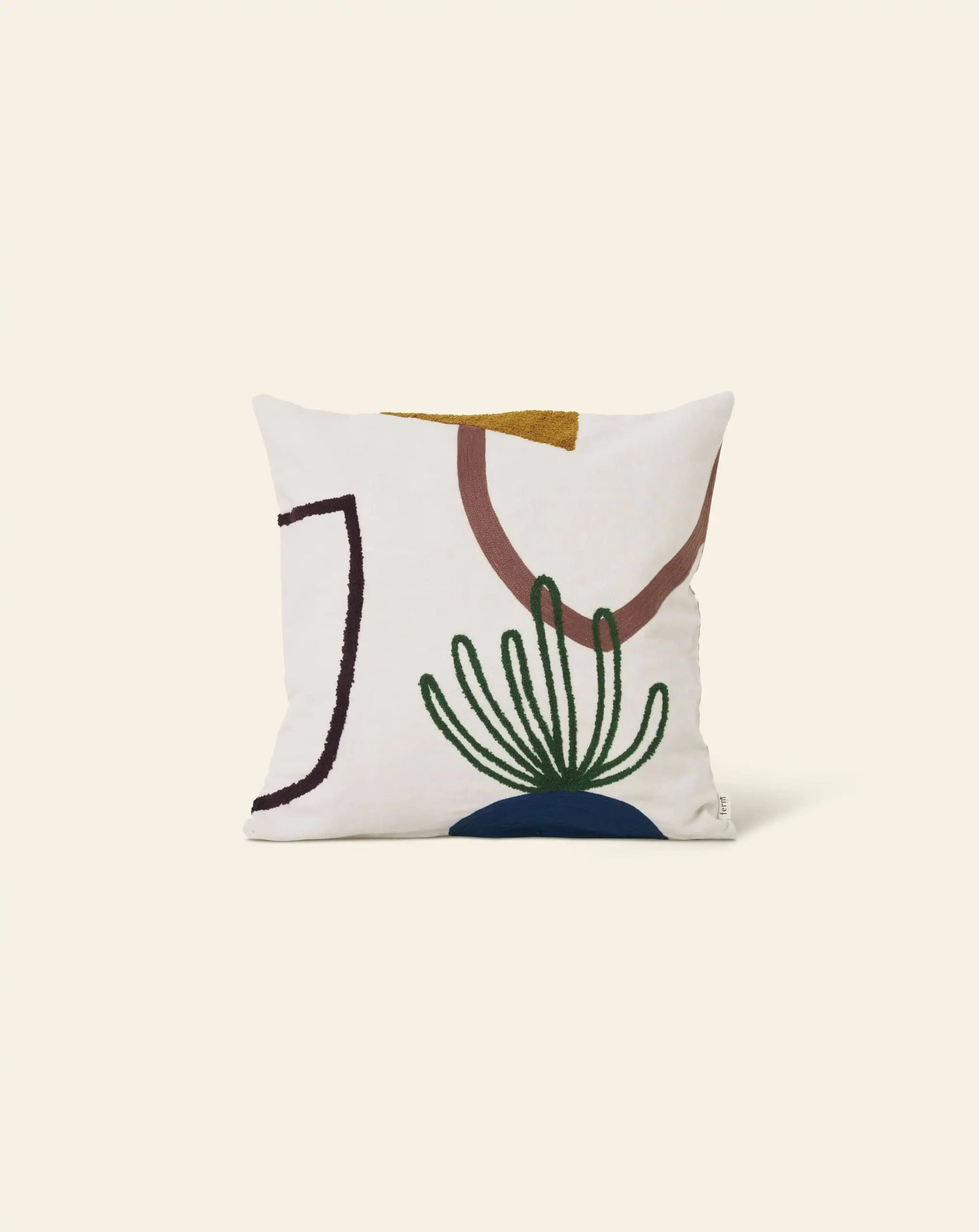 The ferm LIVING Mirage Cushion by ferm LIVING features a modern abstract design with embroidered shapes in brown, gold, blue, green, and black on a cream background—an elegant decorative pillow displayed on a plain cream backdrop.