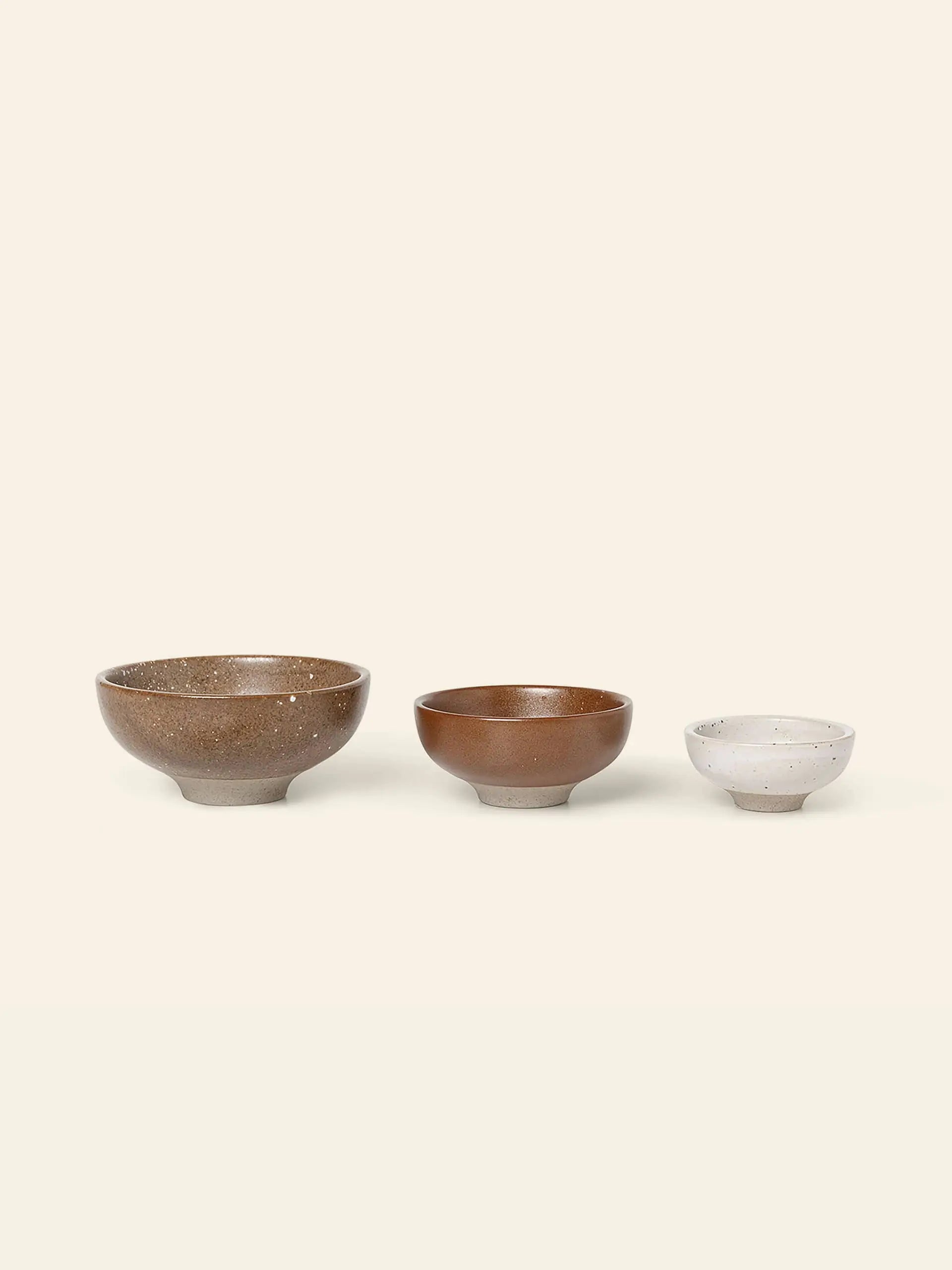 The ferm LIVING Petite Bowls, Set of 3 features natural earthy brown and beige tones arranged from largest to smallest, adding a warm, rustic touch to your dining experience.