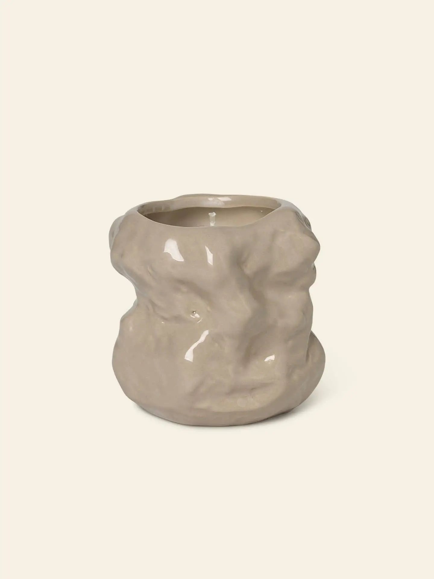 The ferm LIVING Tuck Scented Candle by ferm LIVING features an uneven, organic shape in light beige ceramic, creating a calming ambiance when displayed against a plain, off-white background.
