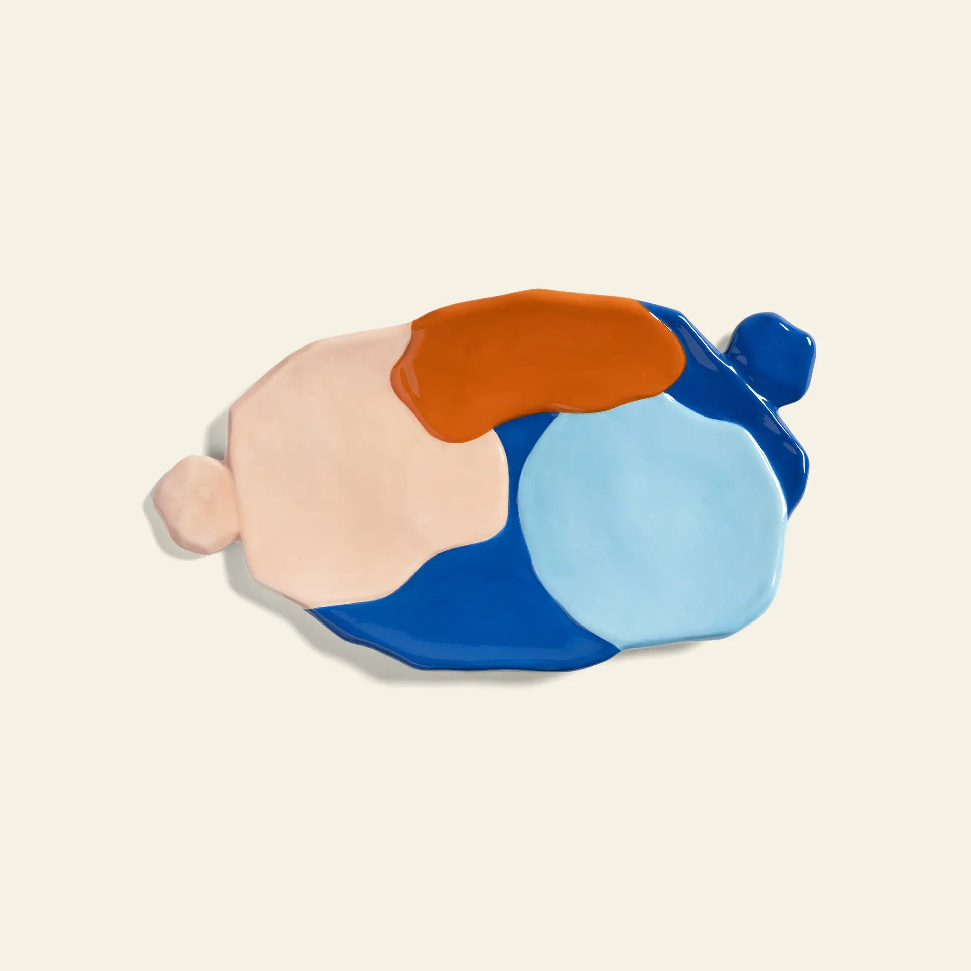 The &klevering Chunky Platter, Large is an abstract ceramic piece featuring irregular shapes in pastel pink, orange, dark blue, and light blue on a plain off-white background for artistic charm.