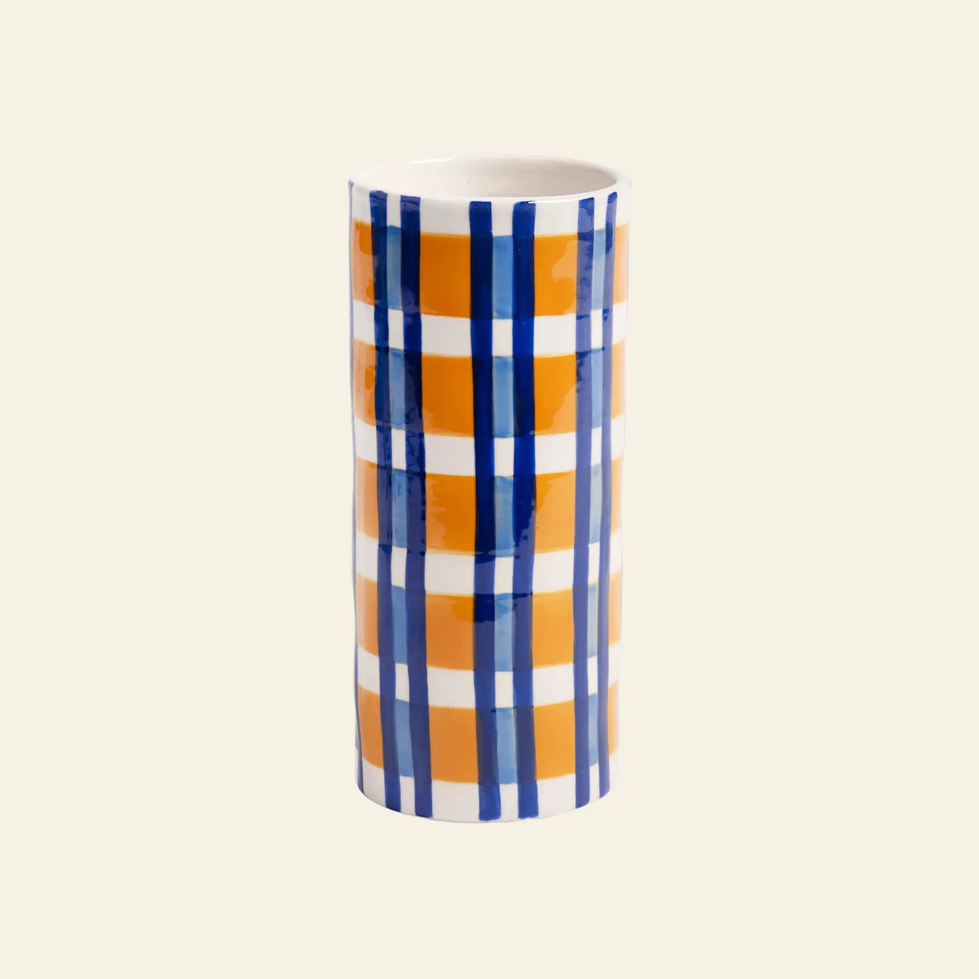 The &klevering Clash Check Vase by &klevering is a cylindrical ceramic vase with a glossy finish, showcasing bold hand-painted orange and blue plaid on white, styled against a plain light beige backdrop.