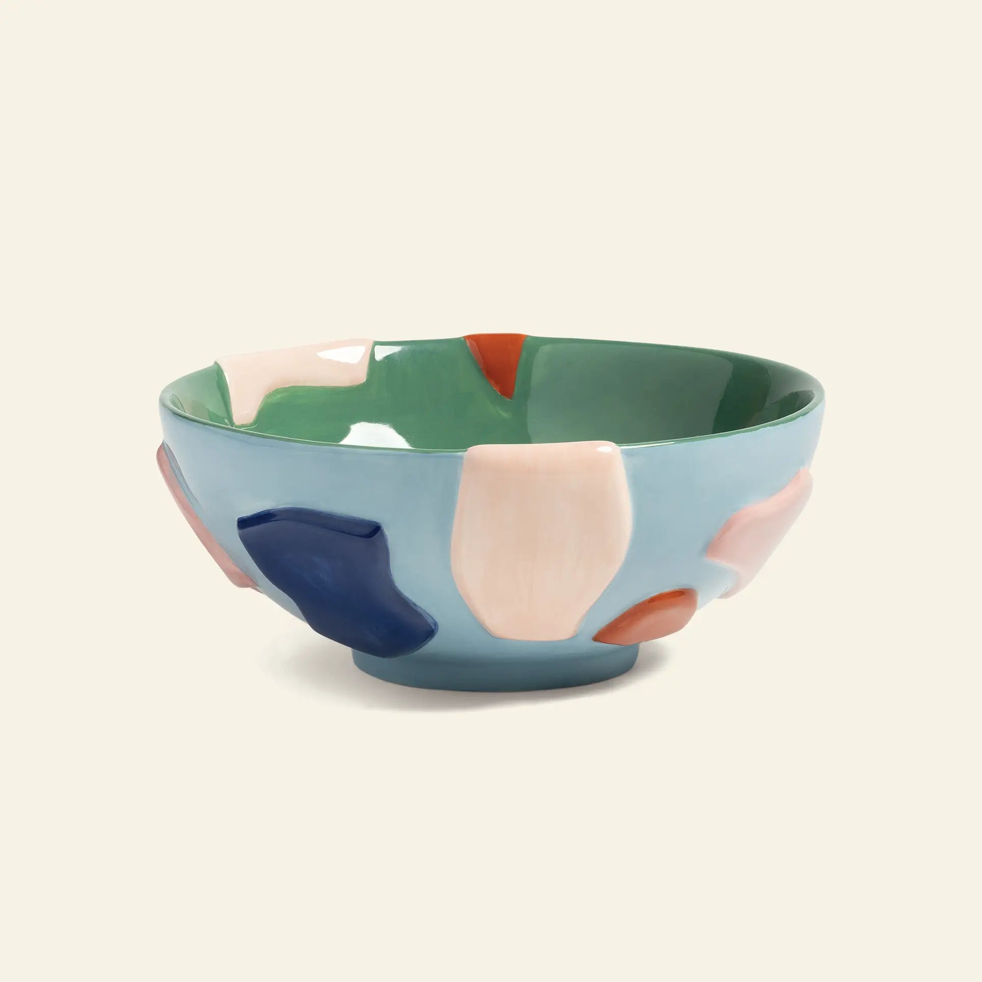 The &klevering Crafty Bowl, Large by &klevering features a light blue ceramic exterior with abstract navy, pink, and red shapes; inside, glossy green with pale pink and red accents make it a unique dining table centerpiece.