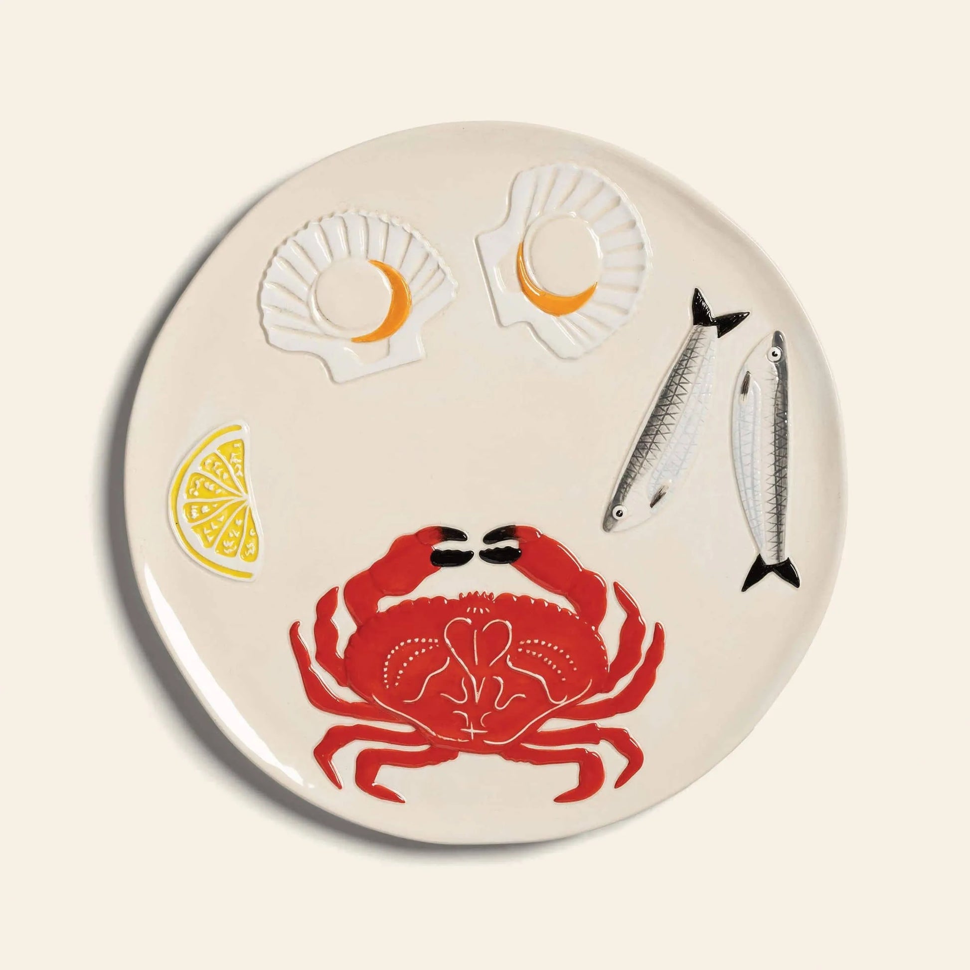The &klevering De La Mer Crab Platter by &klevering is a round white platter with decorative pieces—a red crab, two fish, two yellow-centered scallop shells, and a lemon wedge—arranged in the signature De La Mer style.