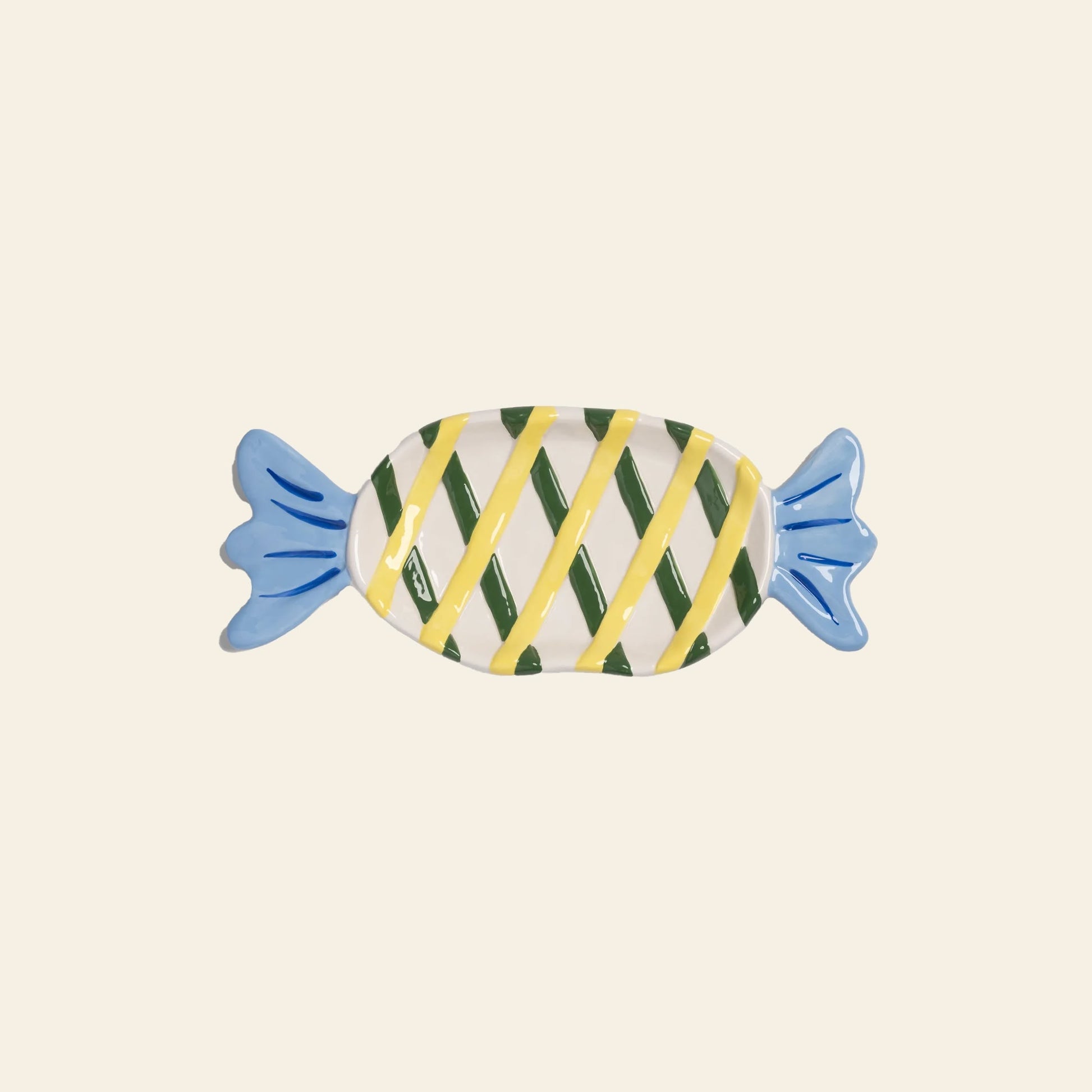 The &klevering Goody Plate, Medium by &klevering features a whimsical ceramic design shaped like wrapped candy, with blue ends and yellow-green diagonal stripes on a beige background—perfect for elevating your dining experience.
