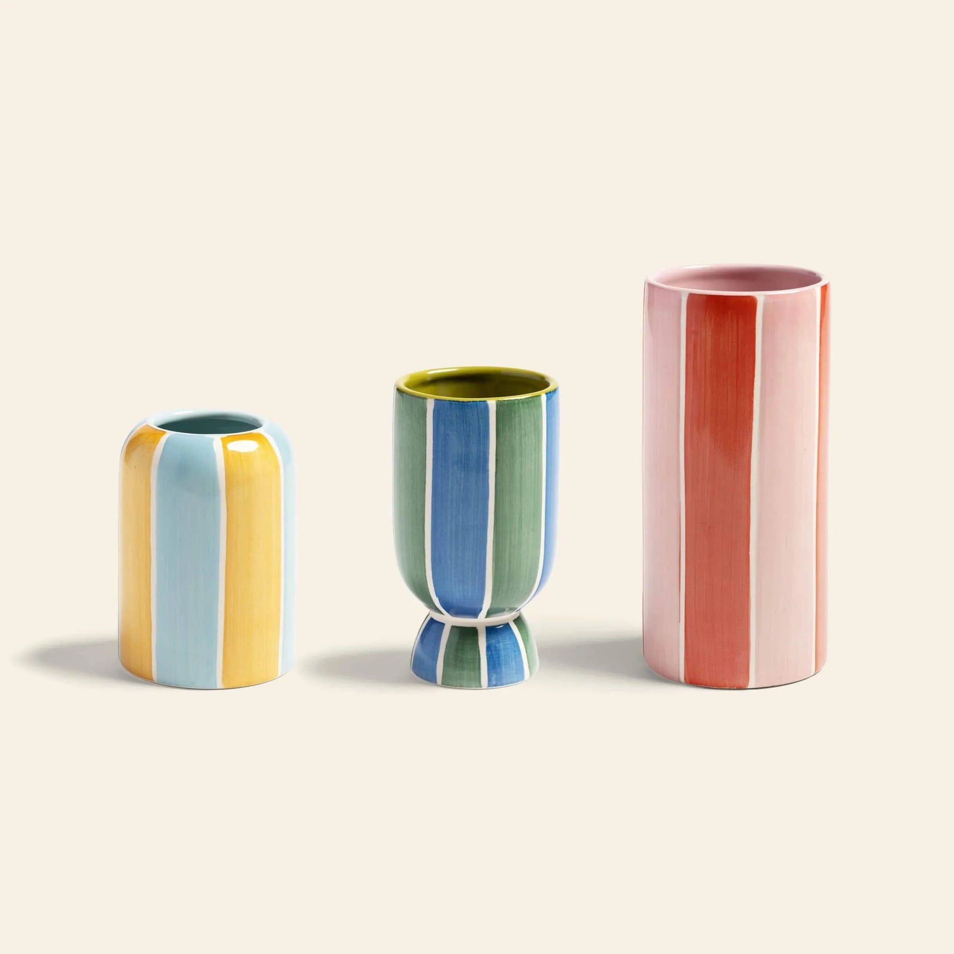 The &klevering Ligne Vase, Set of 3, features geometric vases in varied shapes and sizes with vertical pastel stripes in blue, yellow, green, and pink displayed against a light beige background.