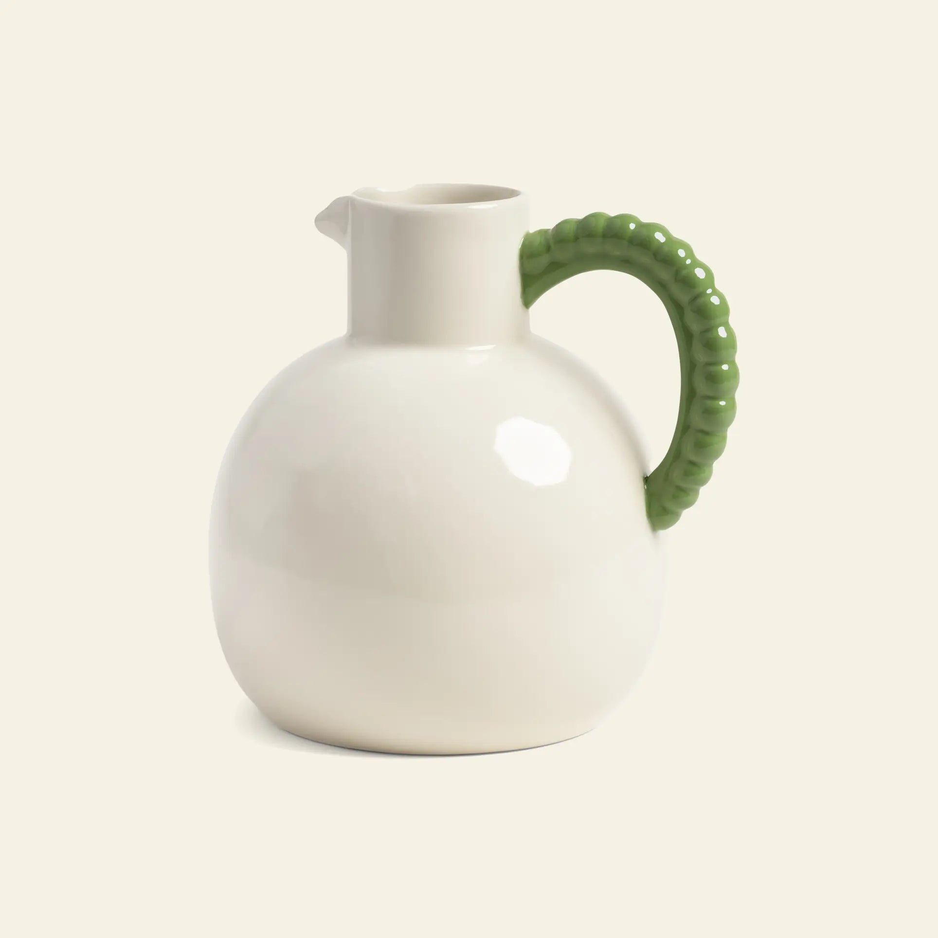 The &klevering Perle Jug by &klevering is a round white ceramic pitcher with a small spout and textured green handle, ideal for summer dining, showcased against a plain beige background.