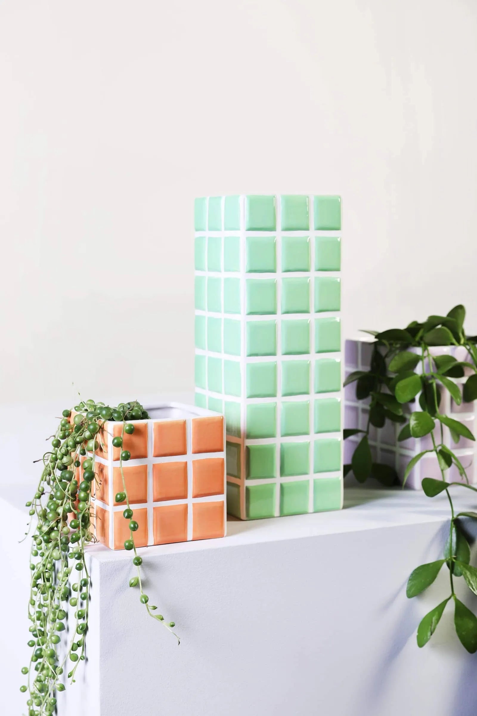 The &klevering Tiled Vase Mint by &klevering features a vibrant tile pattern in green, displayed with cascading greenery on a white surface against a light background.