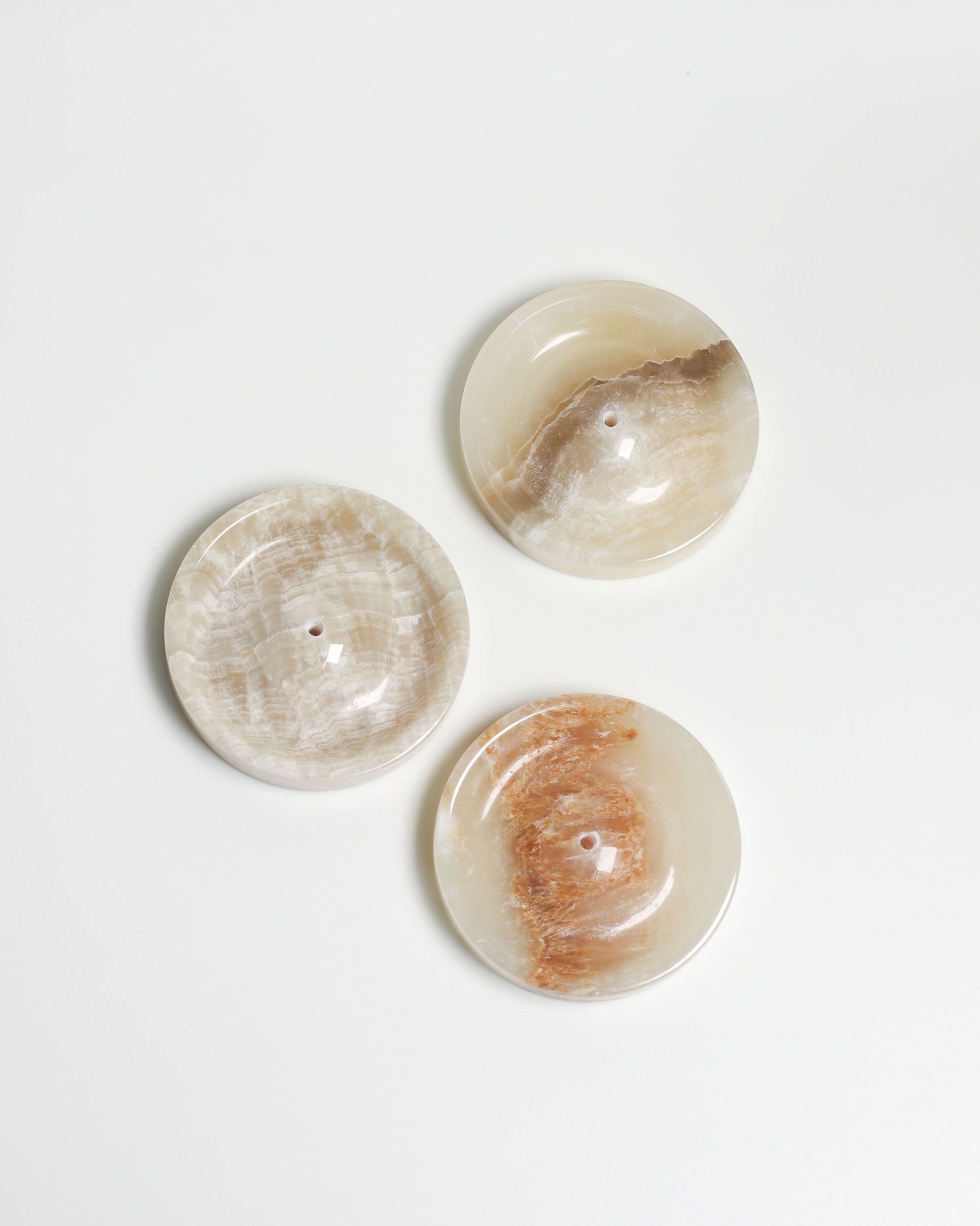 The stillgoods Ebb Incense Holder by stillgoods features three round, polished stone discs with natural beige, brown, and cream marbling—ideal for incense or ikebana—elegantly displayed on a white background.
