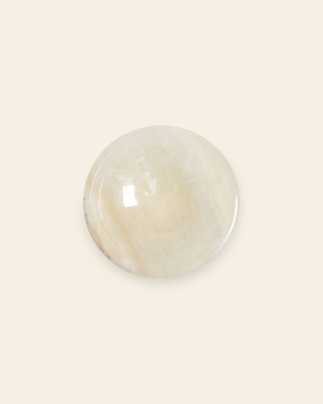 The stillgoods Luna Dish is a round, smooth, light beige gemstone dish with a glossy finish on a cream background—ideal for holding your favorite jewelry or small essentials.